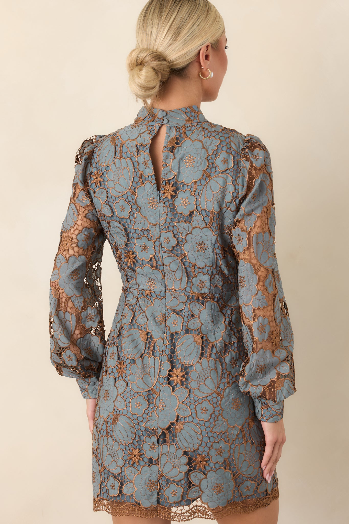 Rear view of the floral lace mini dress highlighting its intricate botanical overlay, long sleeves, high neckline, and concealed zipper.