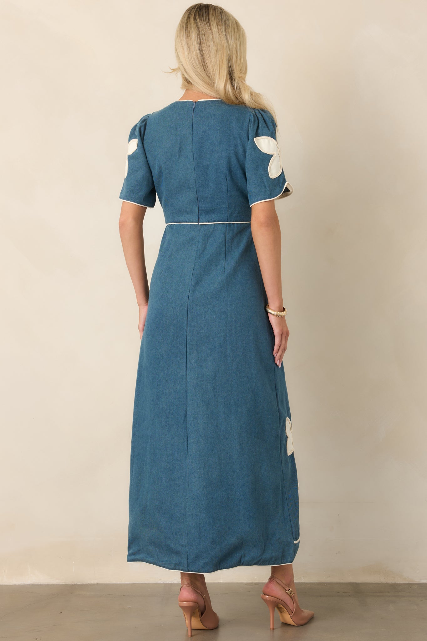 Rear view of the maxi dress showcasing the defined waist, softly flared skirt, coordinating piping, and back zipper closure.