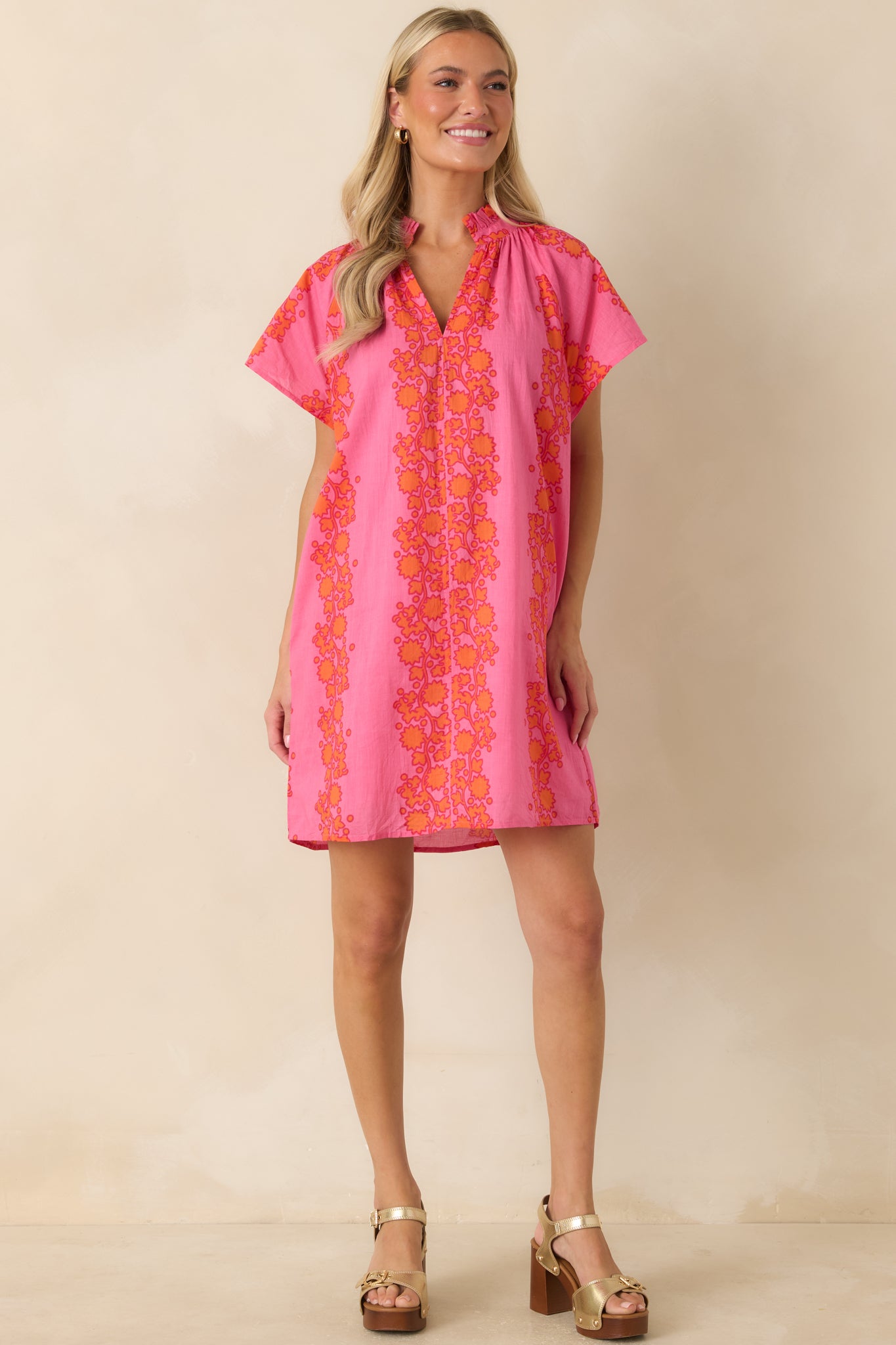 Floral mini dress with a loose silhouette, short sleeves, and playful pink and orange print.