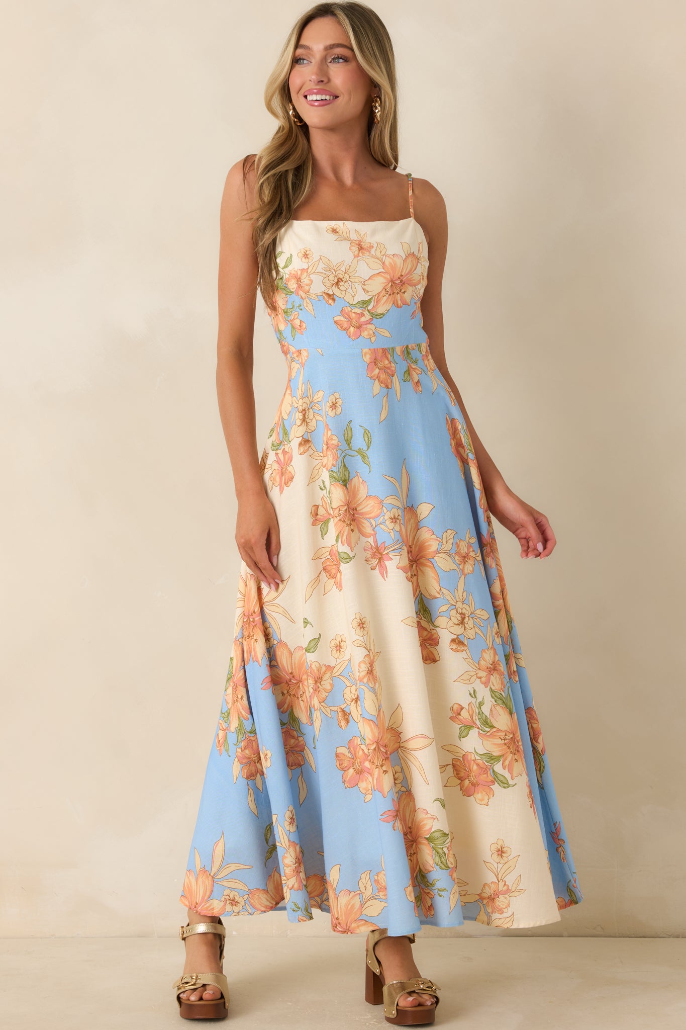 Floral print maxi dress featuring a fitted upper design and a flowing skirt in a blue, ivory, peach, and blush palette.