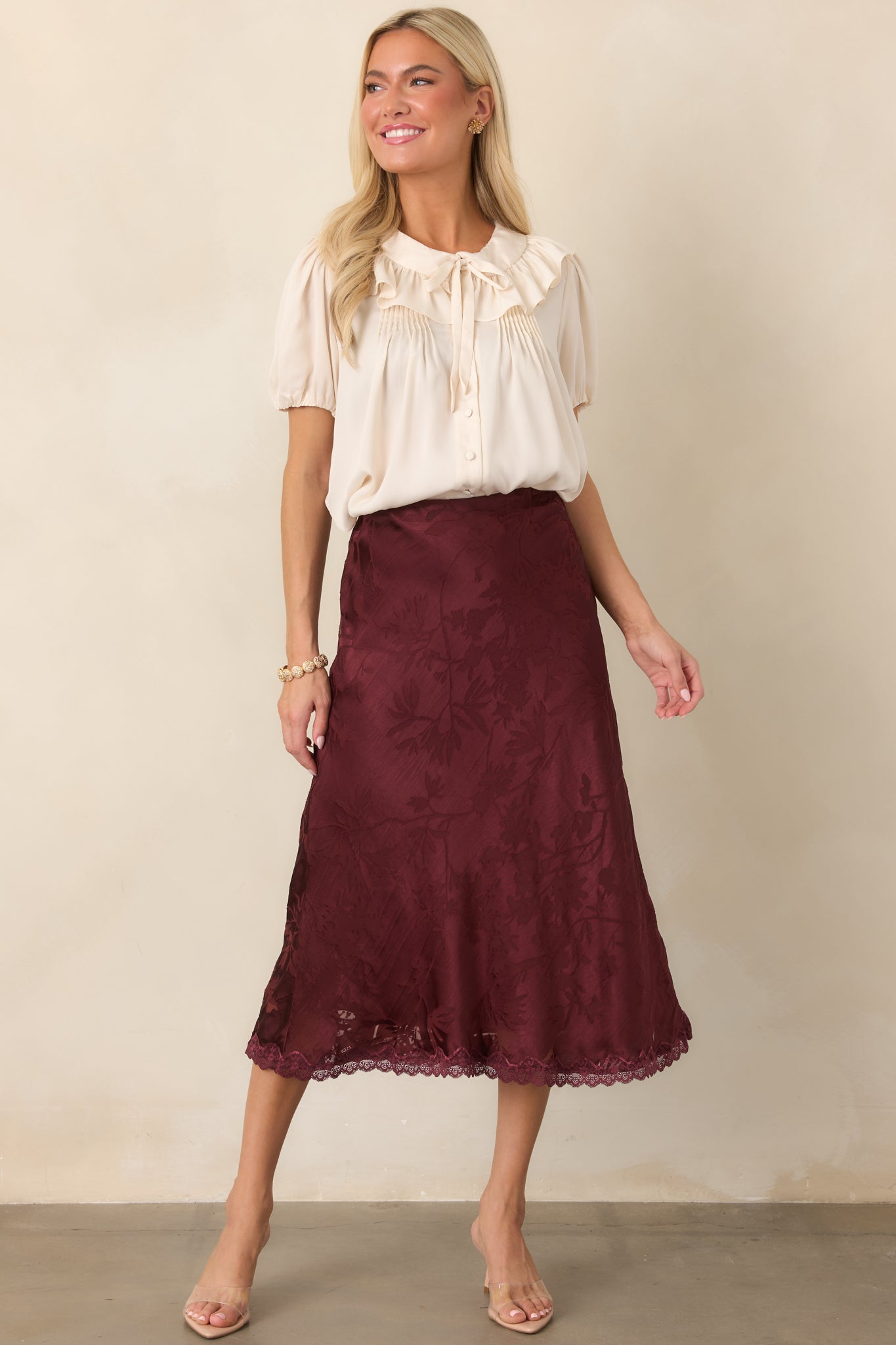 Feminine satin midi skirt showcasing its softly skimming bias-cut shape, subtle floral pattern, and refined lace-trimmed hemline.