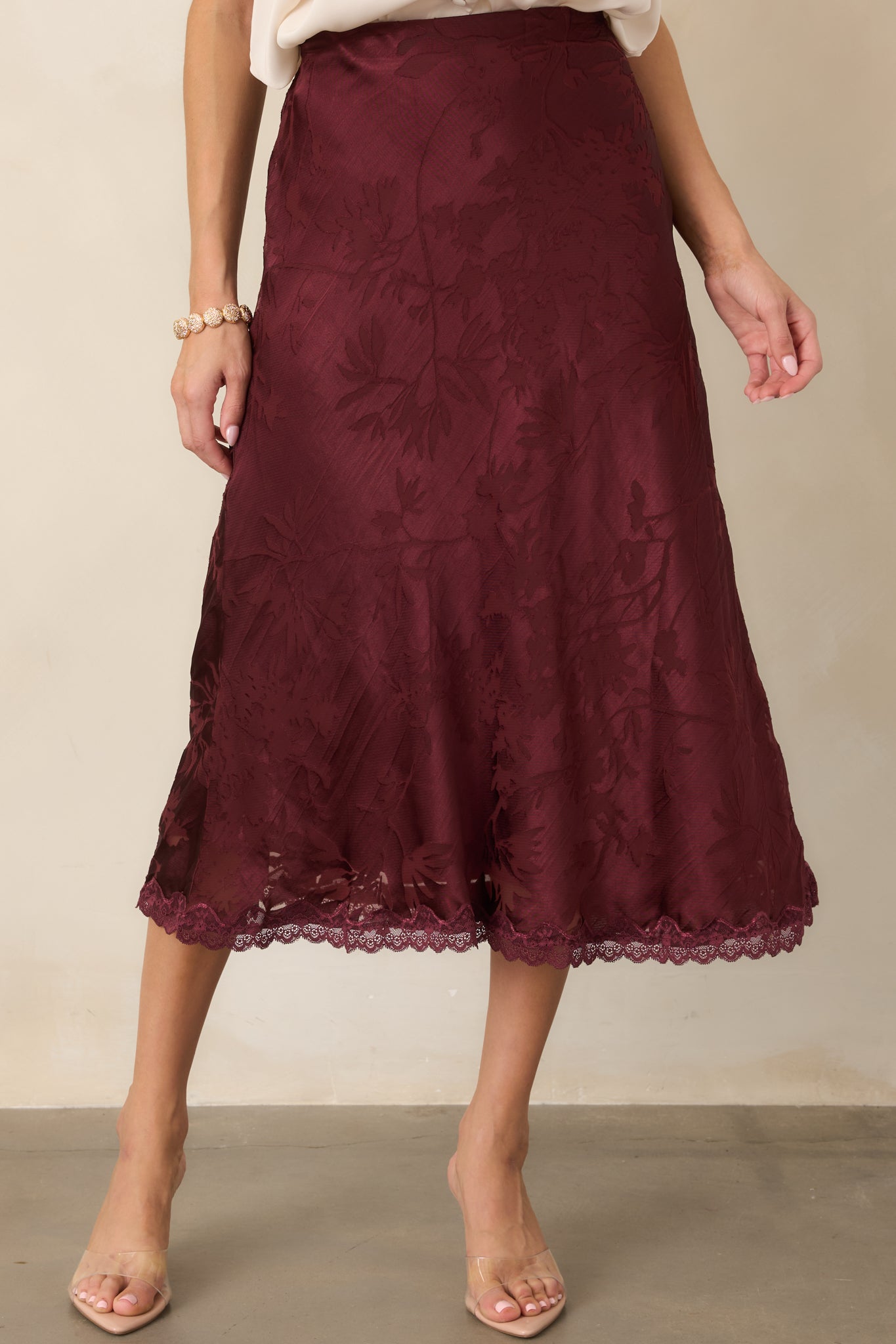 Close view of the feminine midi skirt showcasing its fluid satin texture and intricate floral design.