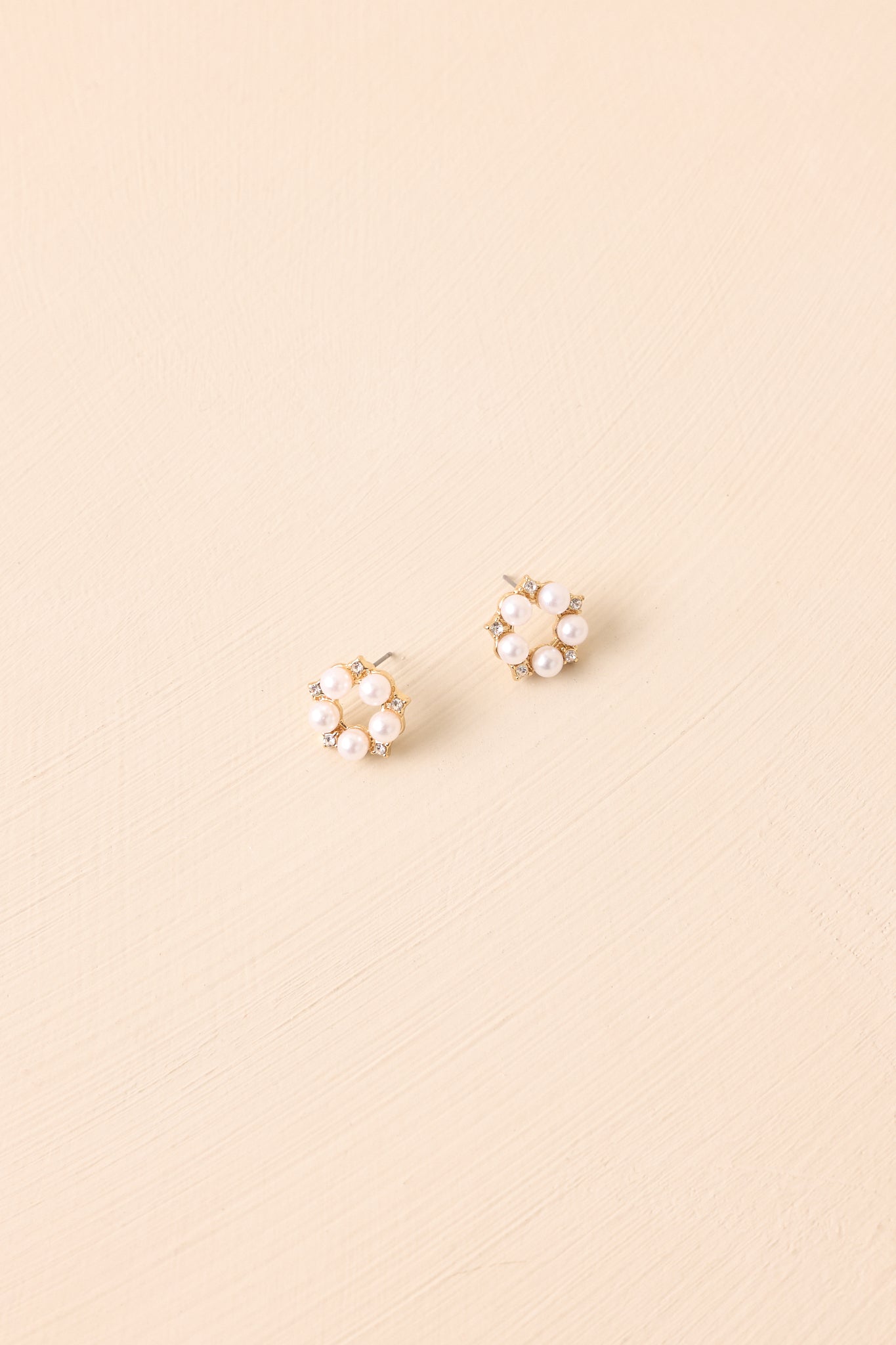 Clustered floral stud earrings displayed on a beige background, showcasing the faux pearl and rhinestone arrangement.