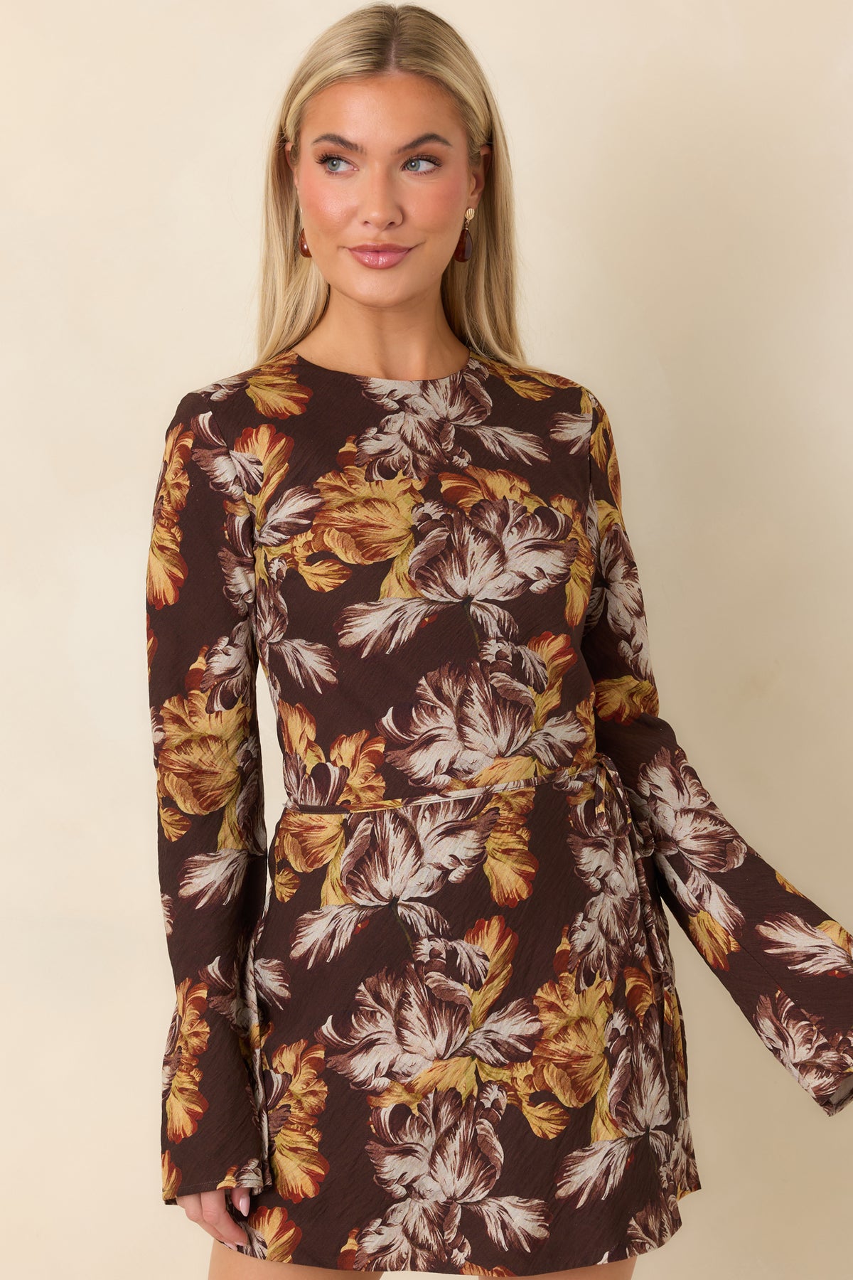 Wrap-style skirt with a side tie creates soft draping and definition at the waist of the floral mini dress.