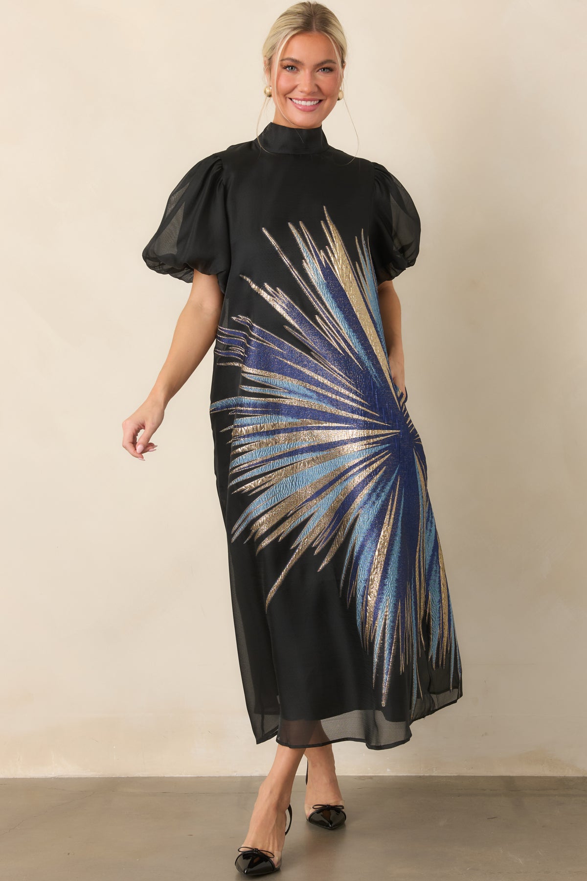 Flowing black midi dress with an artful blue and gold starburst overlay and relaxed A-line silhouette.