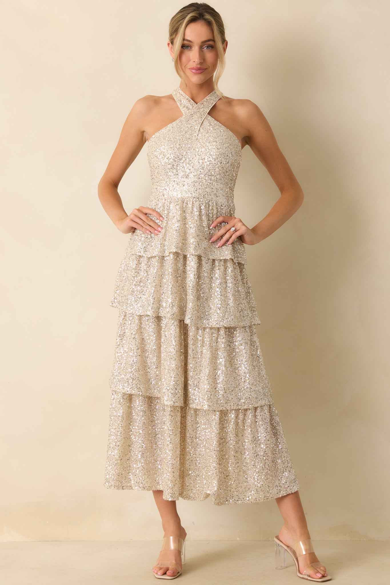 Flowing champagne sequin dress featuring a halter style and layered skirt for a luminous, textured look