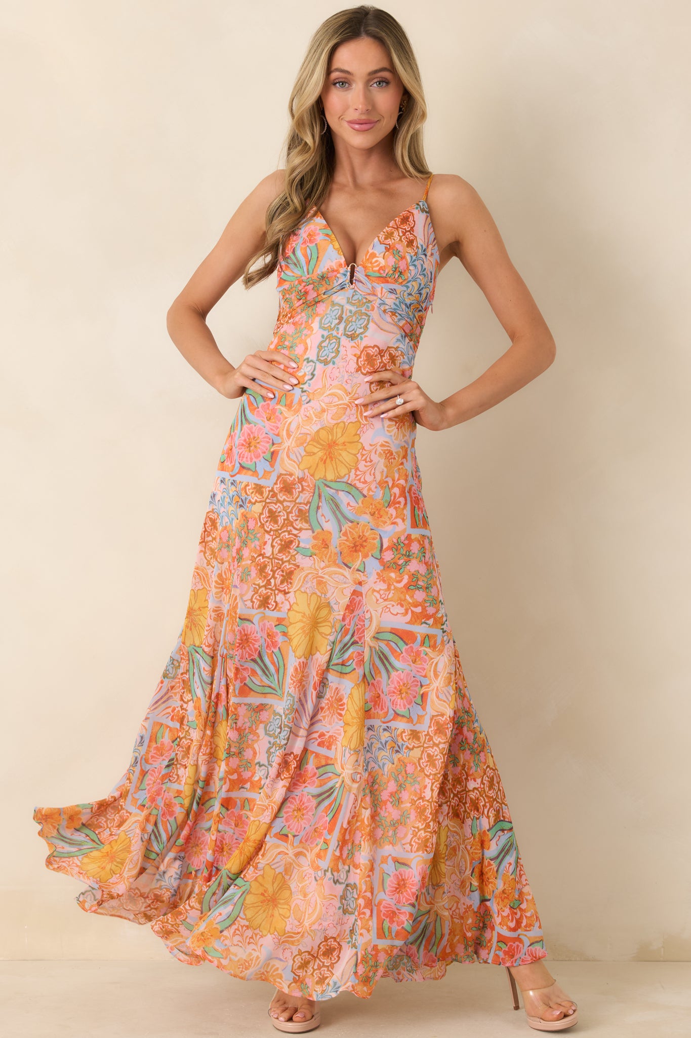 Flowing maxi dress with vibrant pink floral print, plunging V-neckline with center ring detail, adjustable spaghetti straps, and a sweeping hemline.