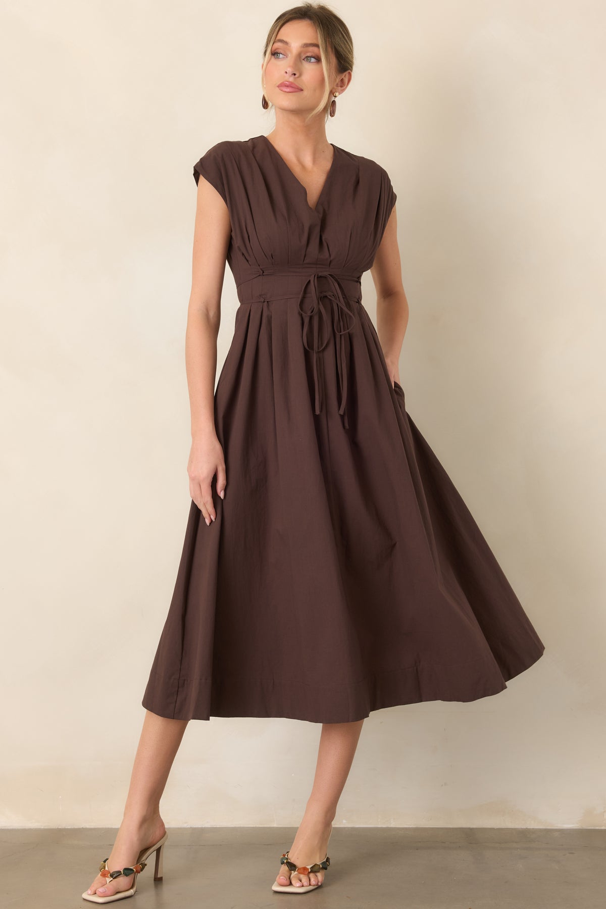 Flowing midi dress with a softly pleated bodice, V-neckline, cap sleeves, double strand self-tie belt, and gathered skirt with a relaxed drape.