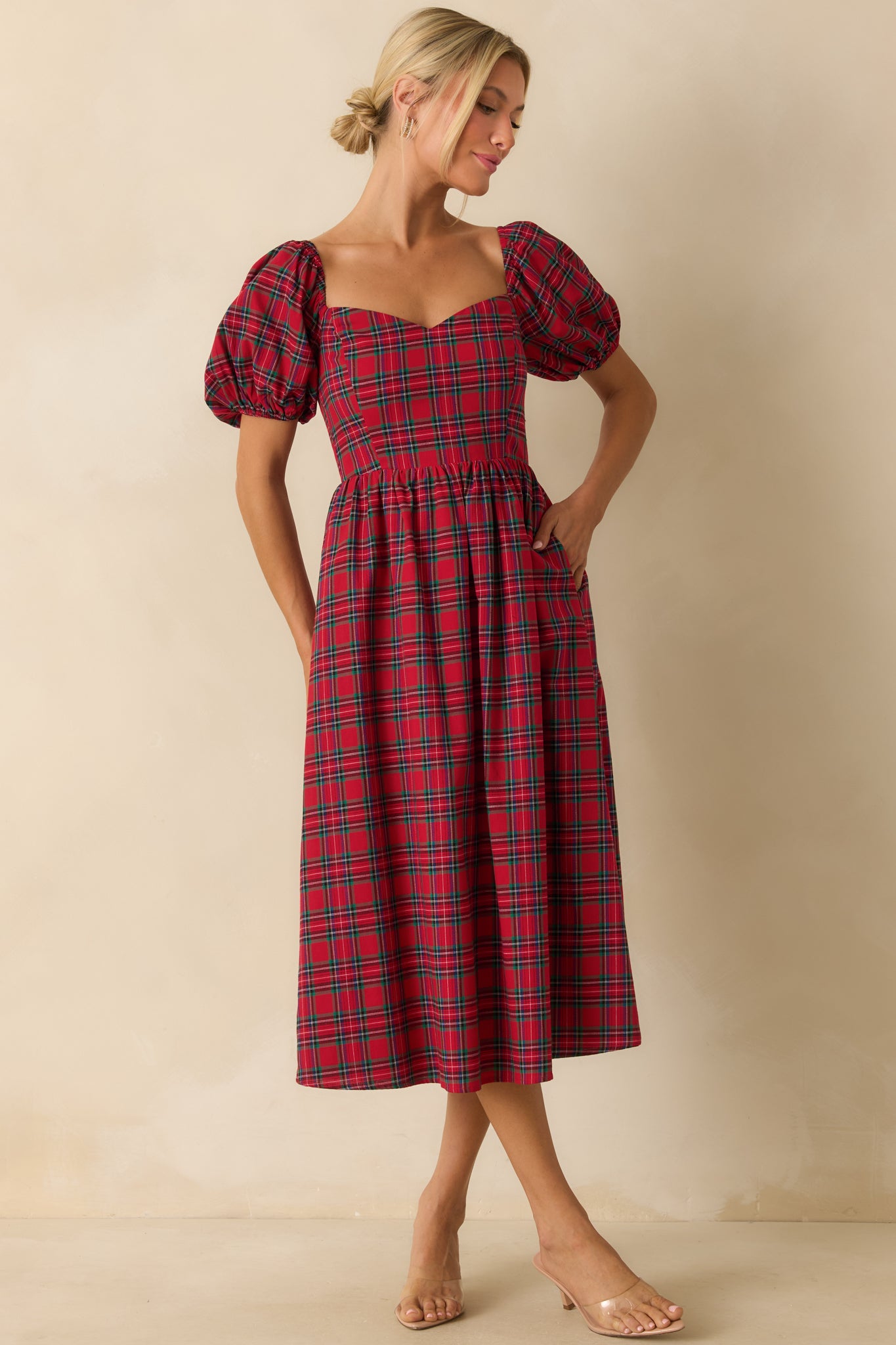 Flowing red plaid dress showing a sweetheart neckline, short puff sleeves, and structured bodice.