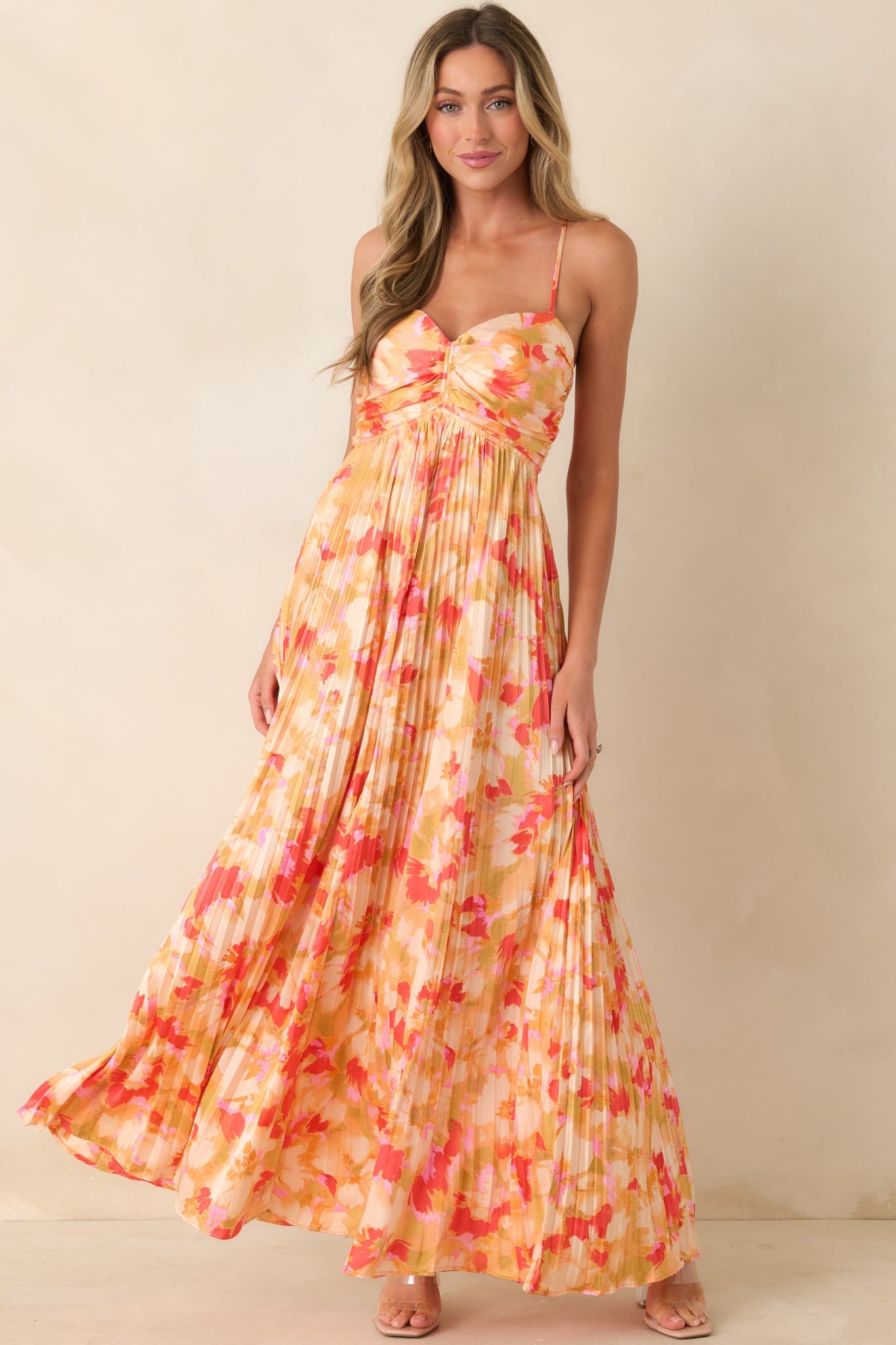 Flowing satin-like maxi dress with pleated skirt, ruched bodice, and adjustable halter-style straps creating an elegant silhouette.

