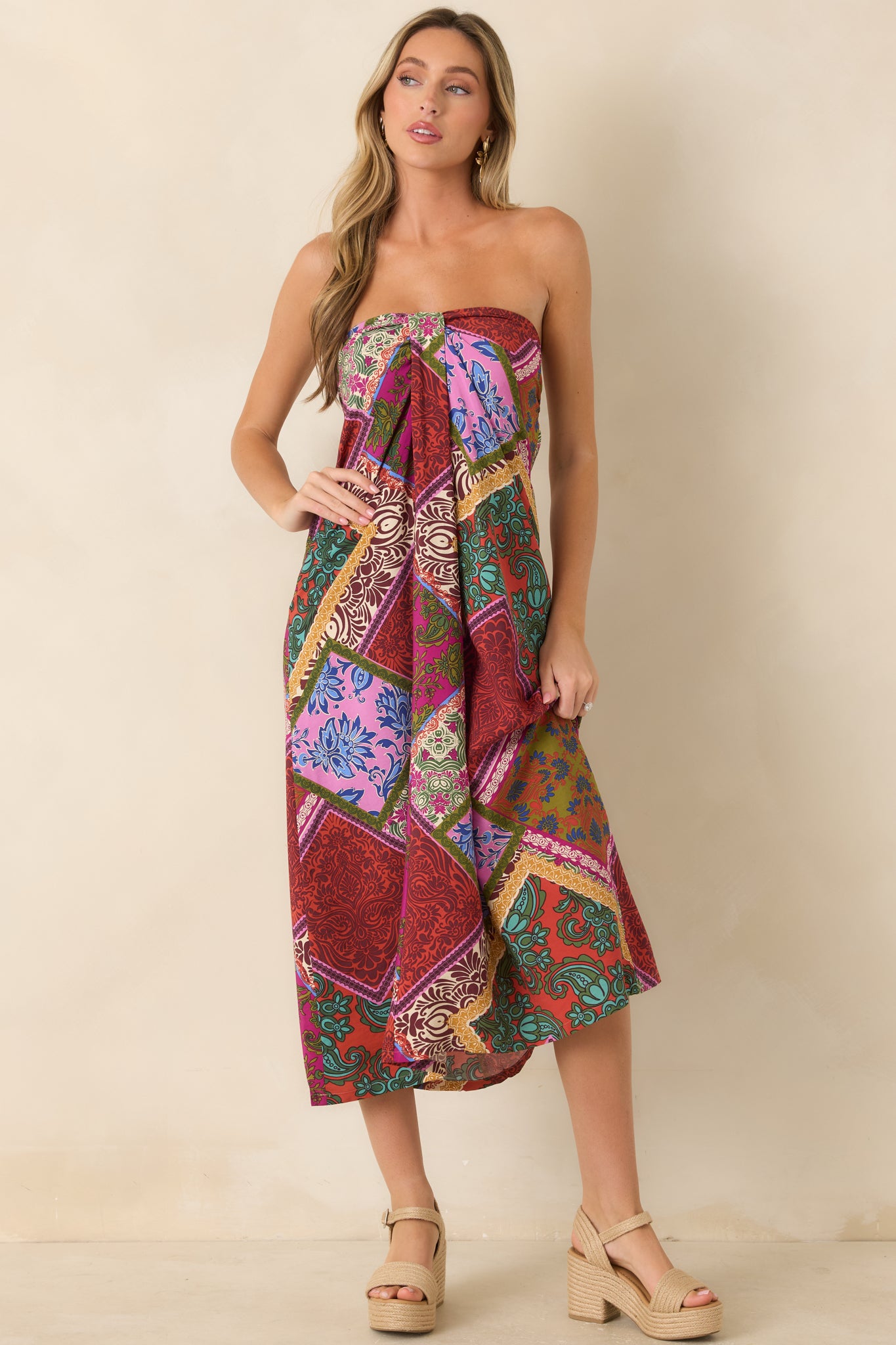 Flowy red multi print midi dress showcasing a structured strapless bodice with a front box pleat for added shape.