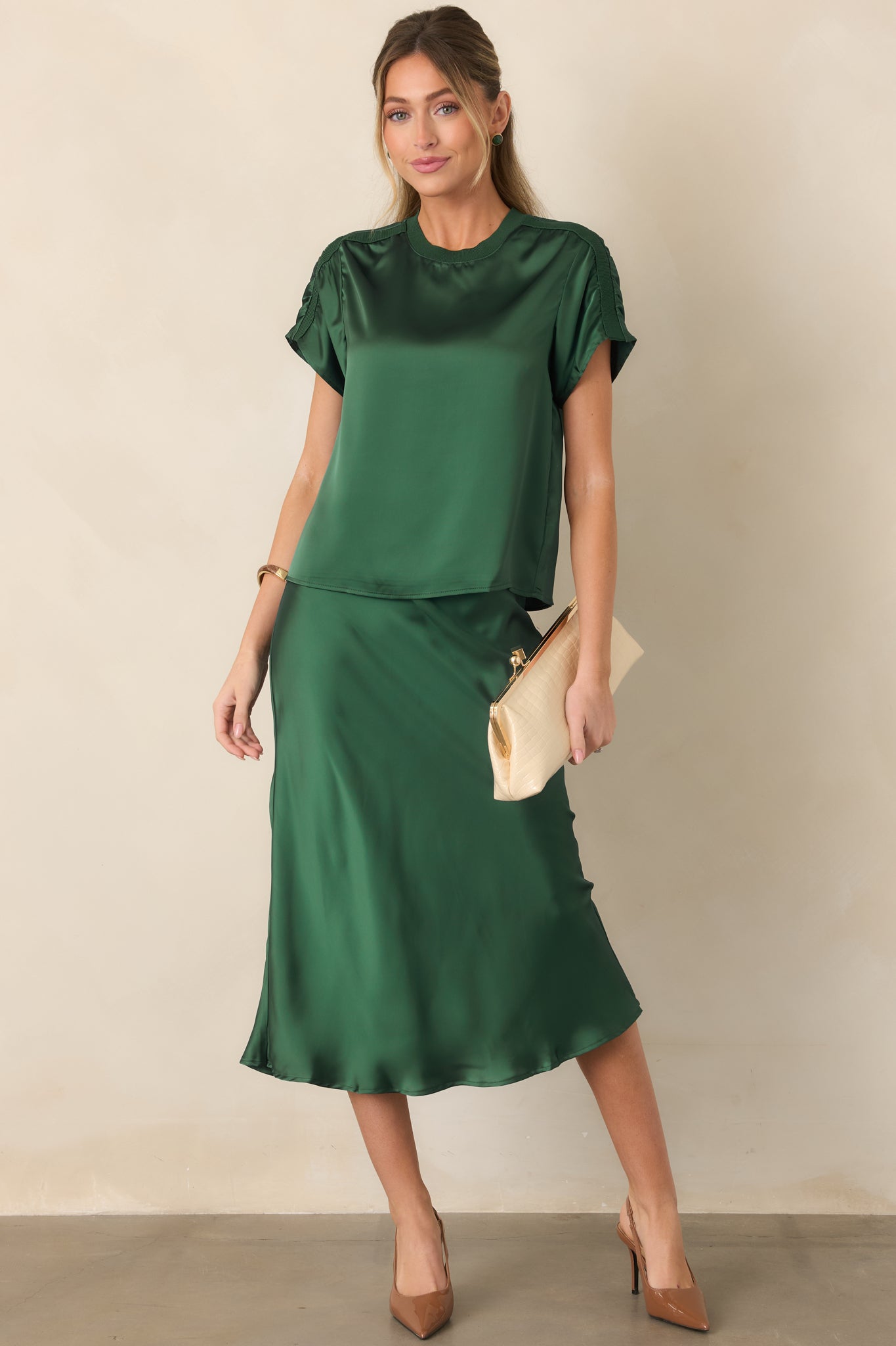 Fluid satin skirt showcasing its smooth finish, comfortable elastic waistband, gently fitted hip line, and graceful midi-length flare.