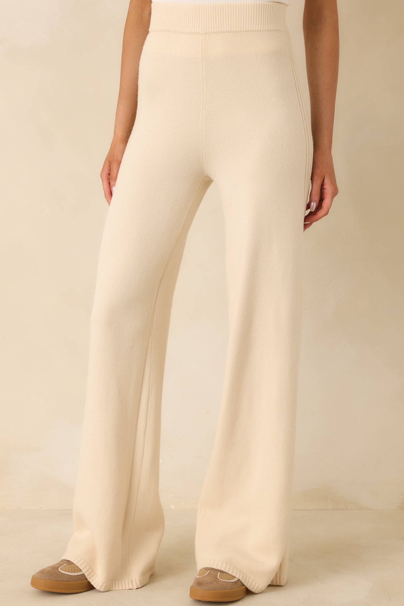 Focused detail of smooth beige knit fabric with straight-leg design.