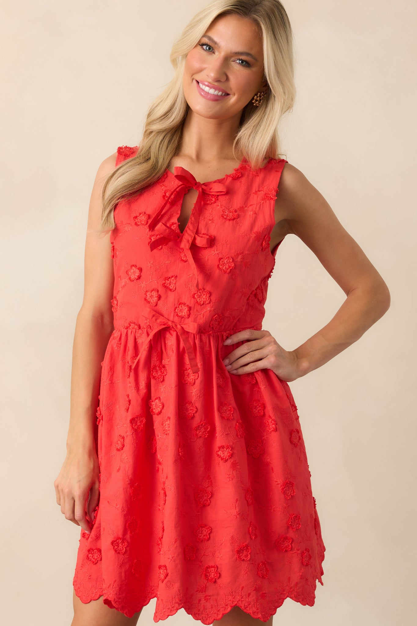 A focused view of the scalloped hemline and self-tie bow front of the red mini dress.
