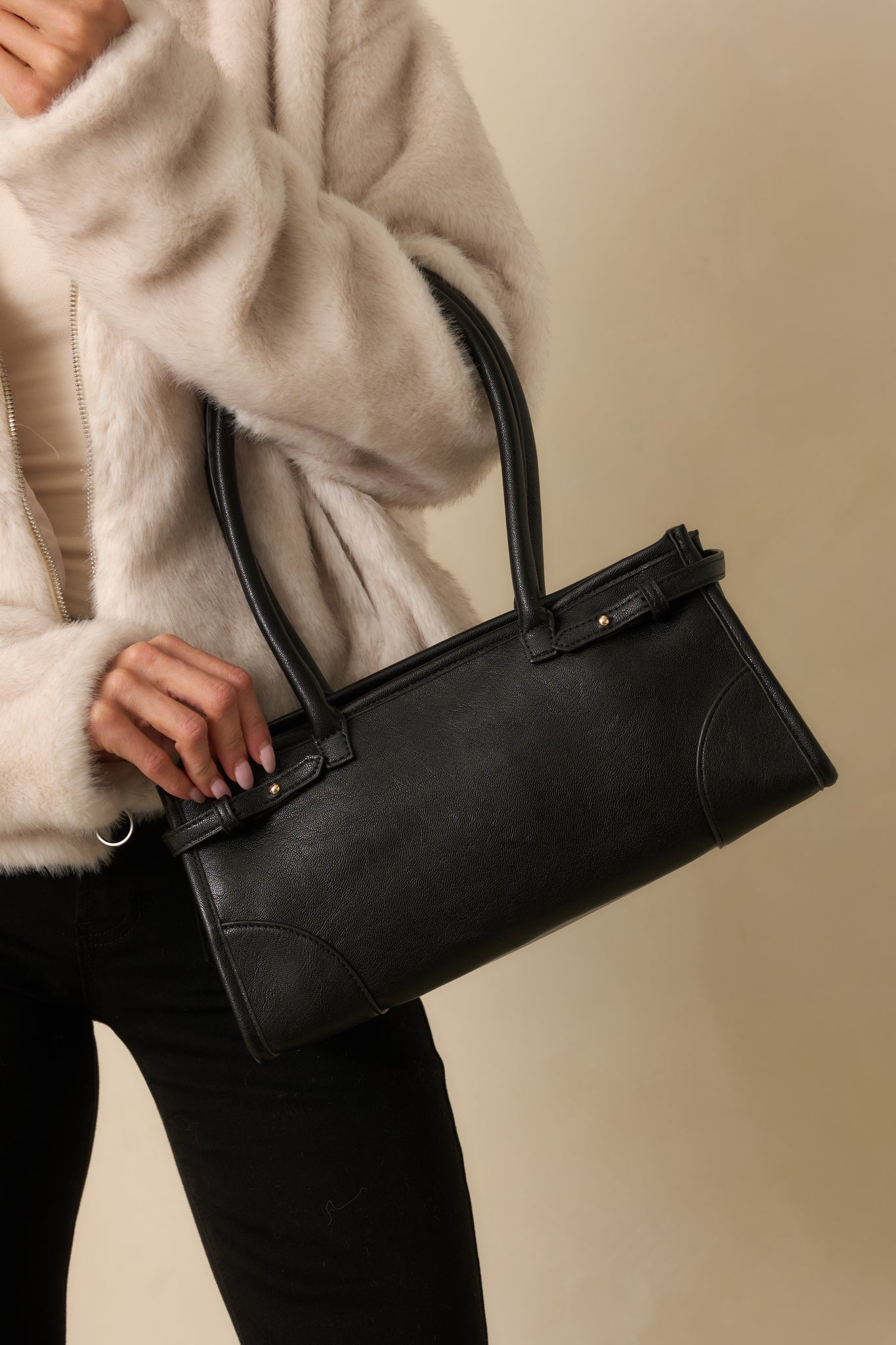Cropped photo focusing on the top handles, zip closure, and smooth faux leather texture.