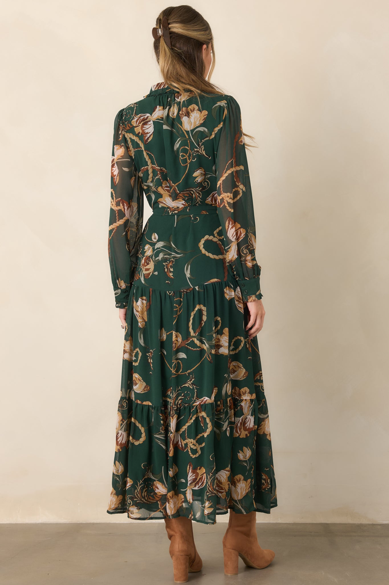 Rear view of the forest green floral maxi dress showcasing its sheer long sleeves, defined waist, and flowing tiered skirt.