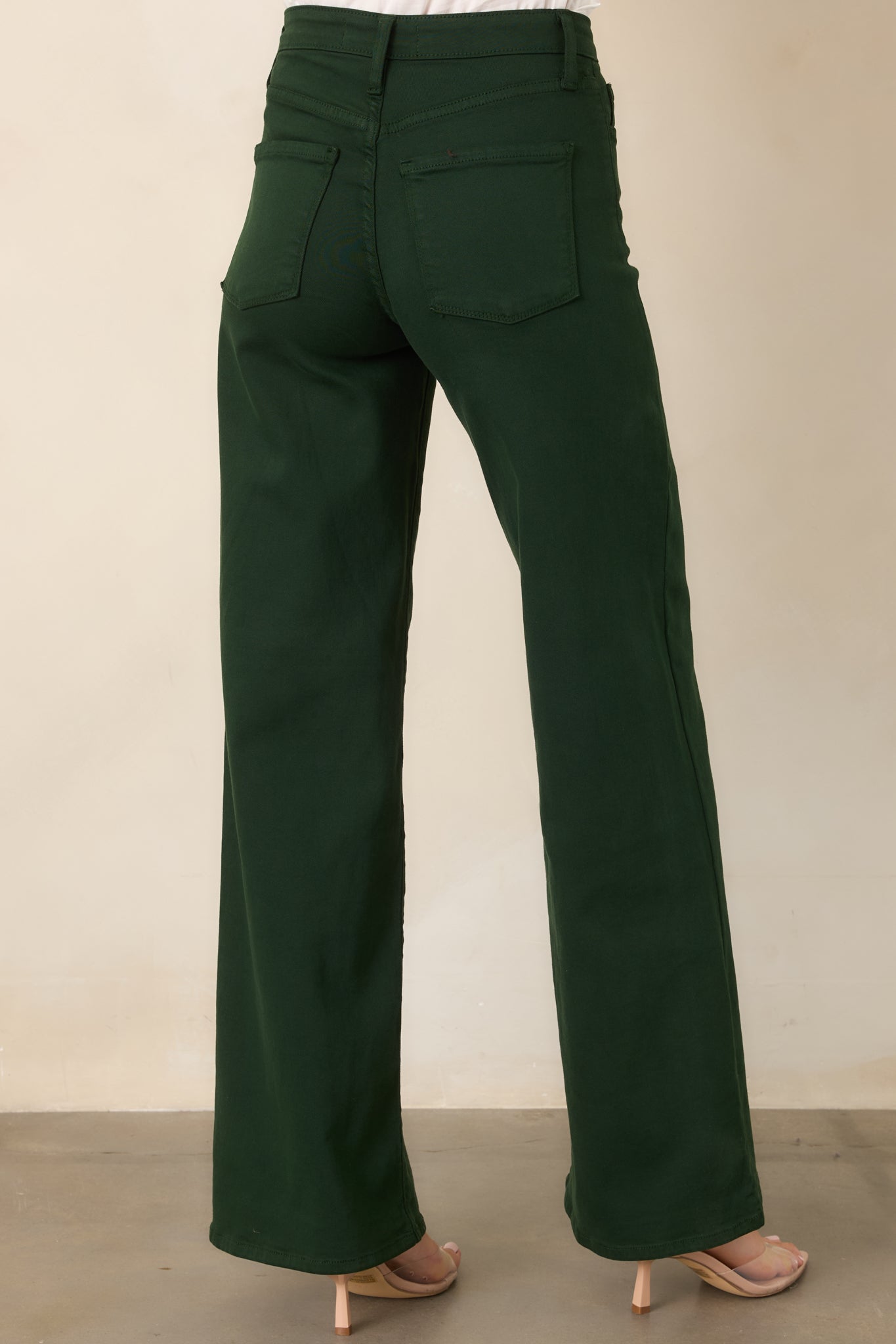 Rear view of the forest green wide-leg pants showcasing the high-rise waistband, smooth denim finish, and elongated silhouette.
