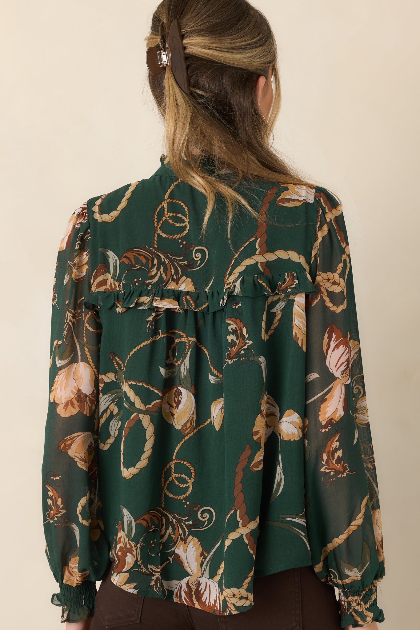 Rear view of the forest green blouse showcasing the relaxed silhouette, ruffle-trimmed yoke, and long sheer sleeves with smocked cuffs.