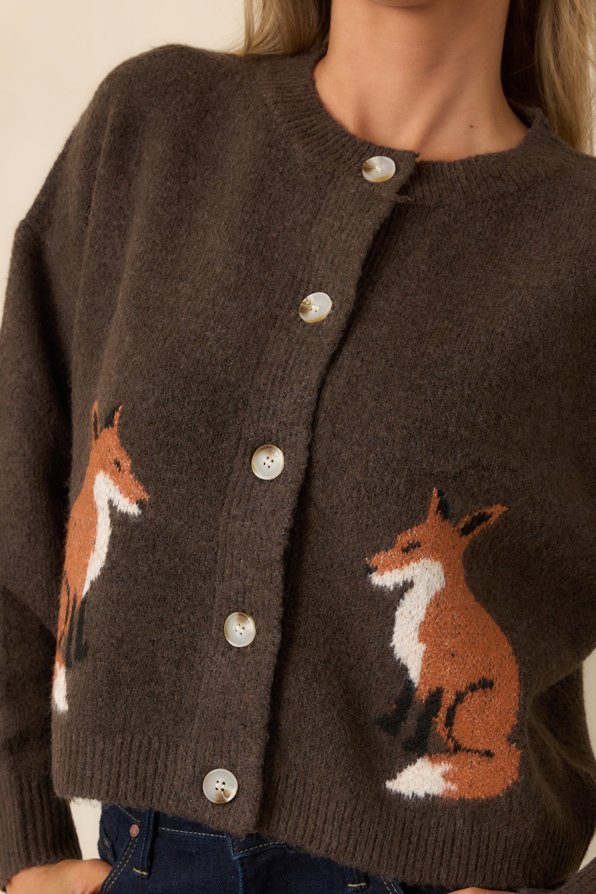Close-up of the cardigan’s fox motifs, marbled buttons, and textured chocolate brown knit.