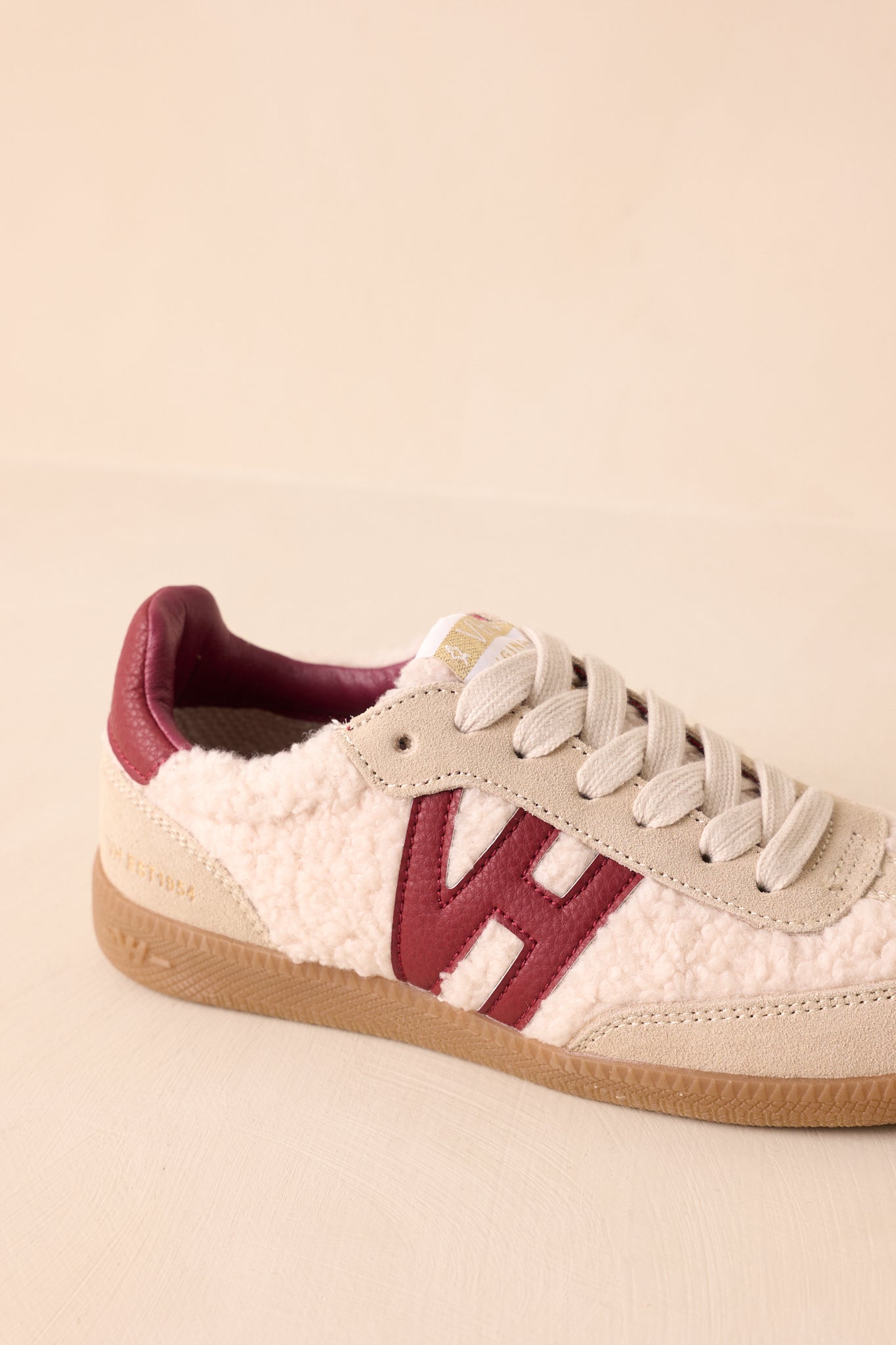 Angled front view highlighting padded collar, lace-up closure, and gold logo detail on the tongue.