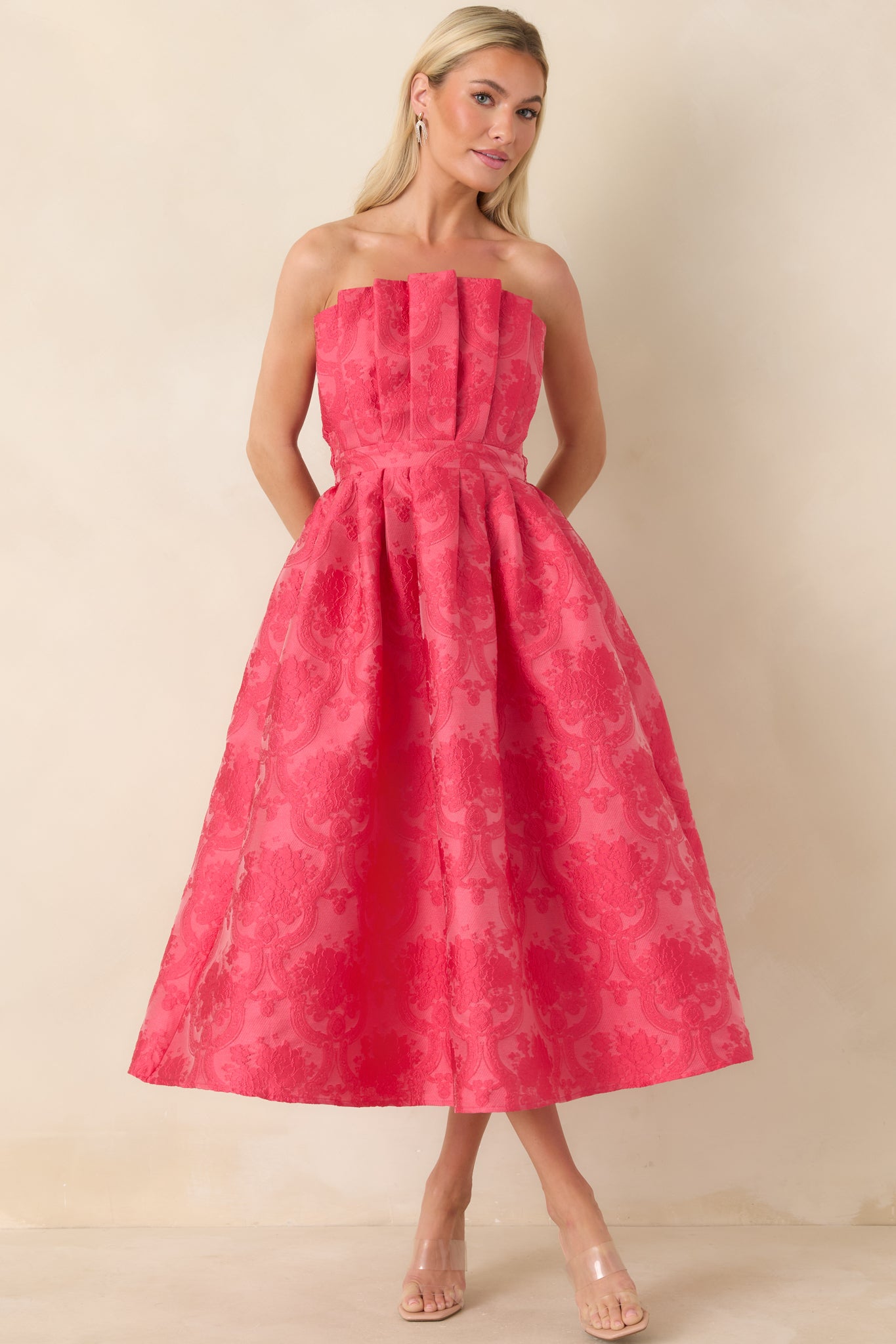 Front-facing angle of elegant pink midi dress highlighting the structured pleats and functional hip pockets.
