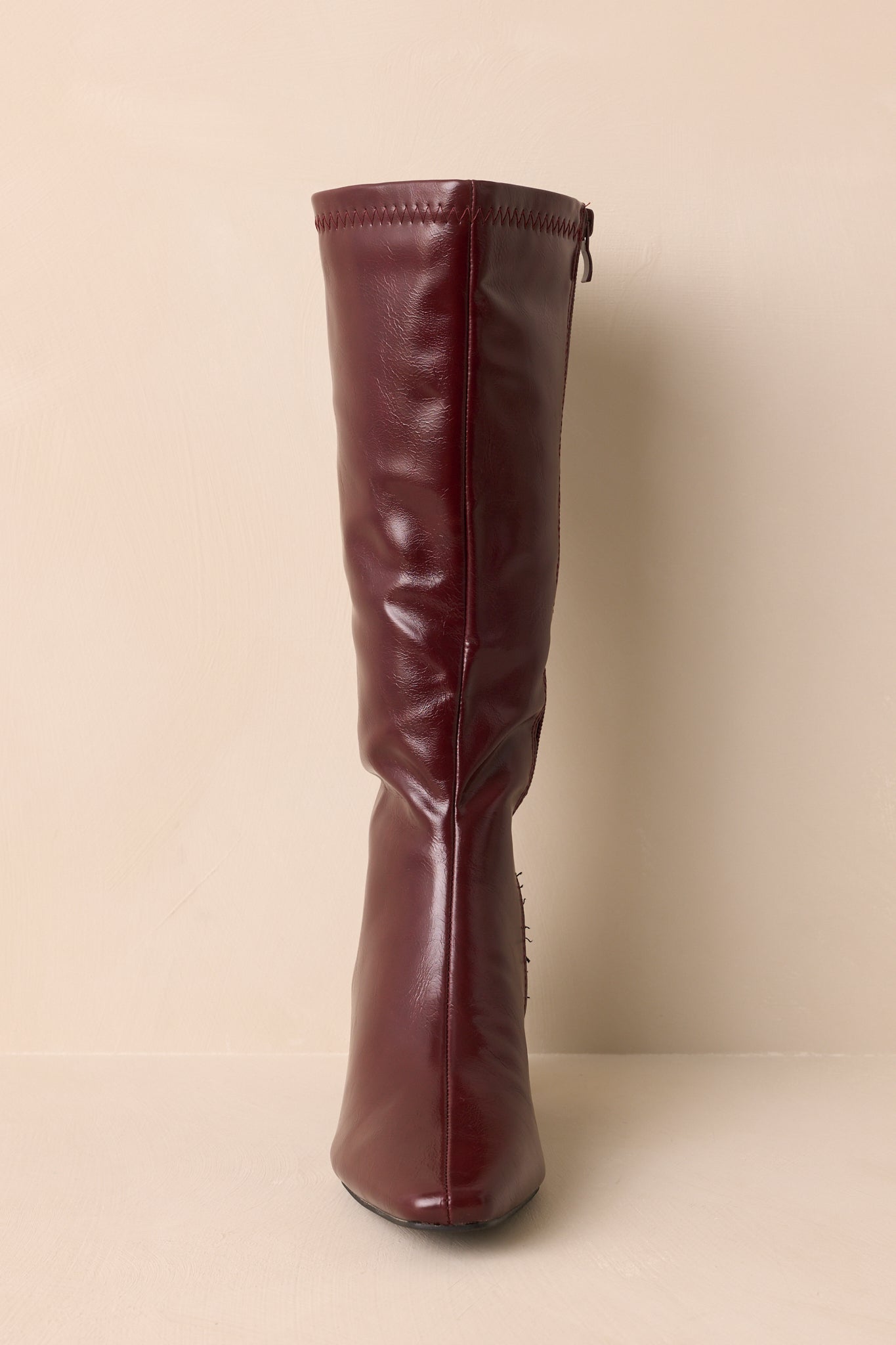 Front angled view of wine red boots showing pointed toe and smooth faux leather finish.