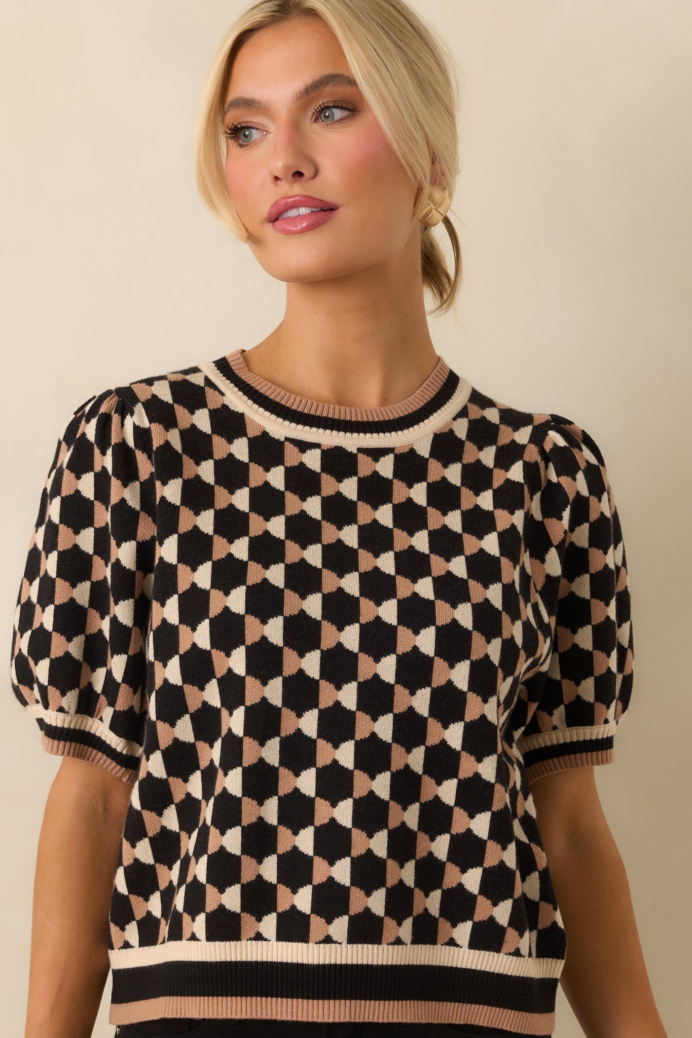 Front crop focusing on short puff sleeves, crew neckline, and allover black and beige pattern.
