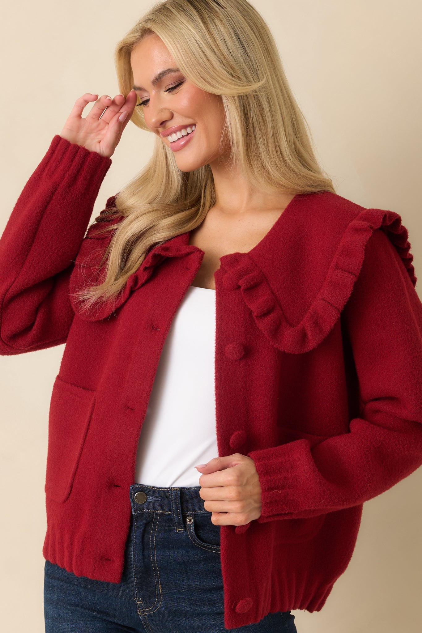 Front detail of long-sleeve red cardigan highlighting ribbed trim and patch pockets.
