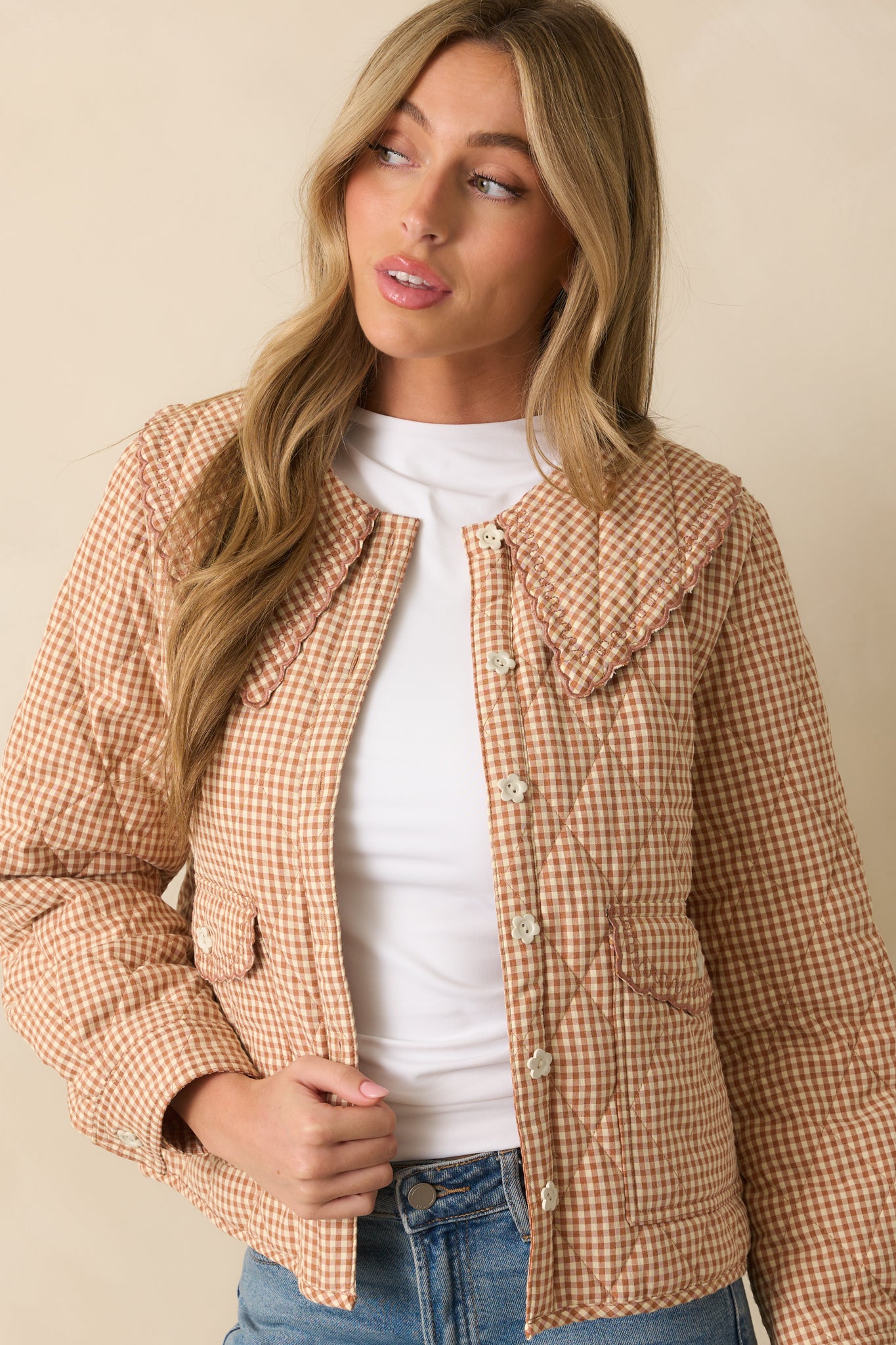 Focus on front flap pockets and ivory flower buttons on the gingham jacket.
