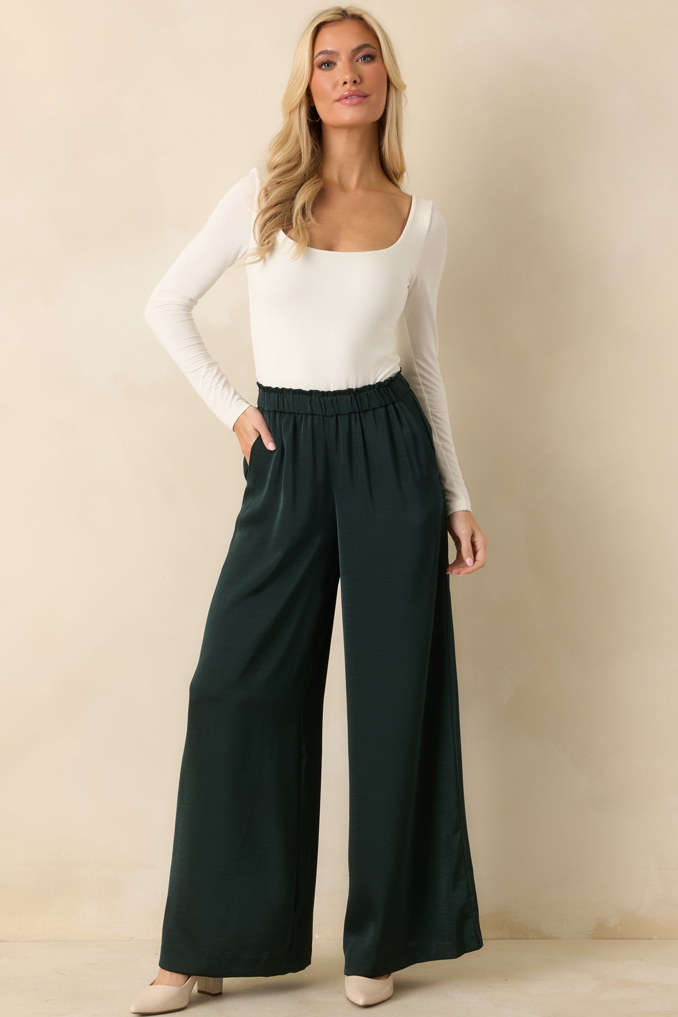 Front view of green satin wide-leg pants showing relaxed silhouette and smooth drape.