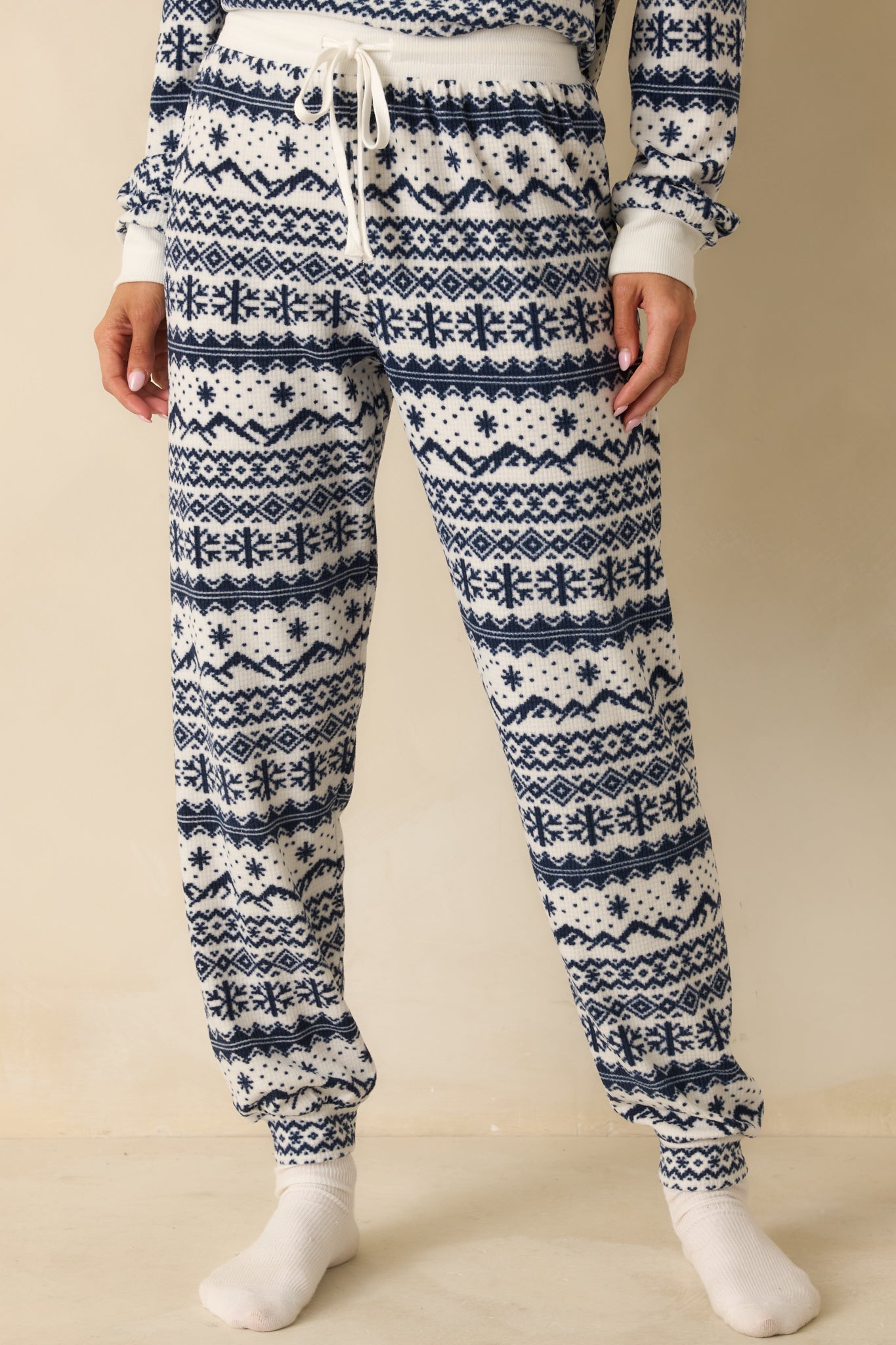 Detail of front of pajama jogger pants, emphasizing drawstring waist, side pockets, and textured brushed knit fabric.