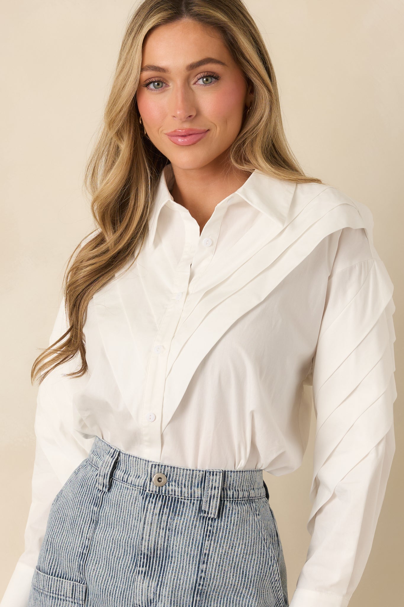 Front placket and pleated shoulder design on a crisp white cotton button-up blouse.