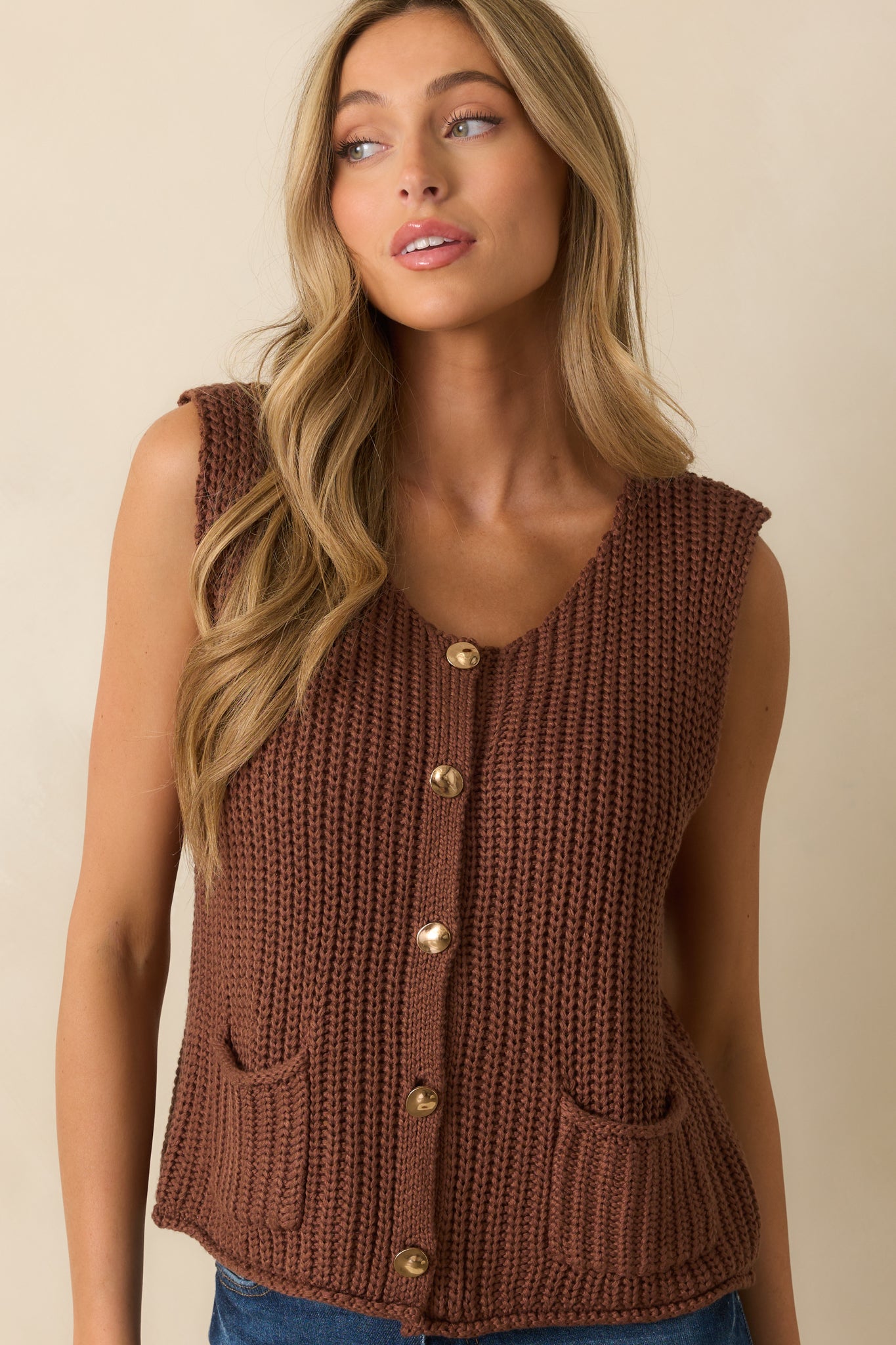 Close-up cropped view of the front pocket and button design, showing the gold hardware and knit texture.