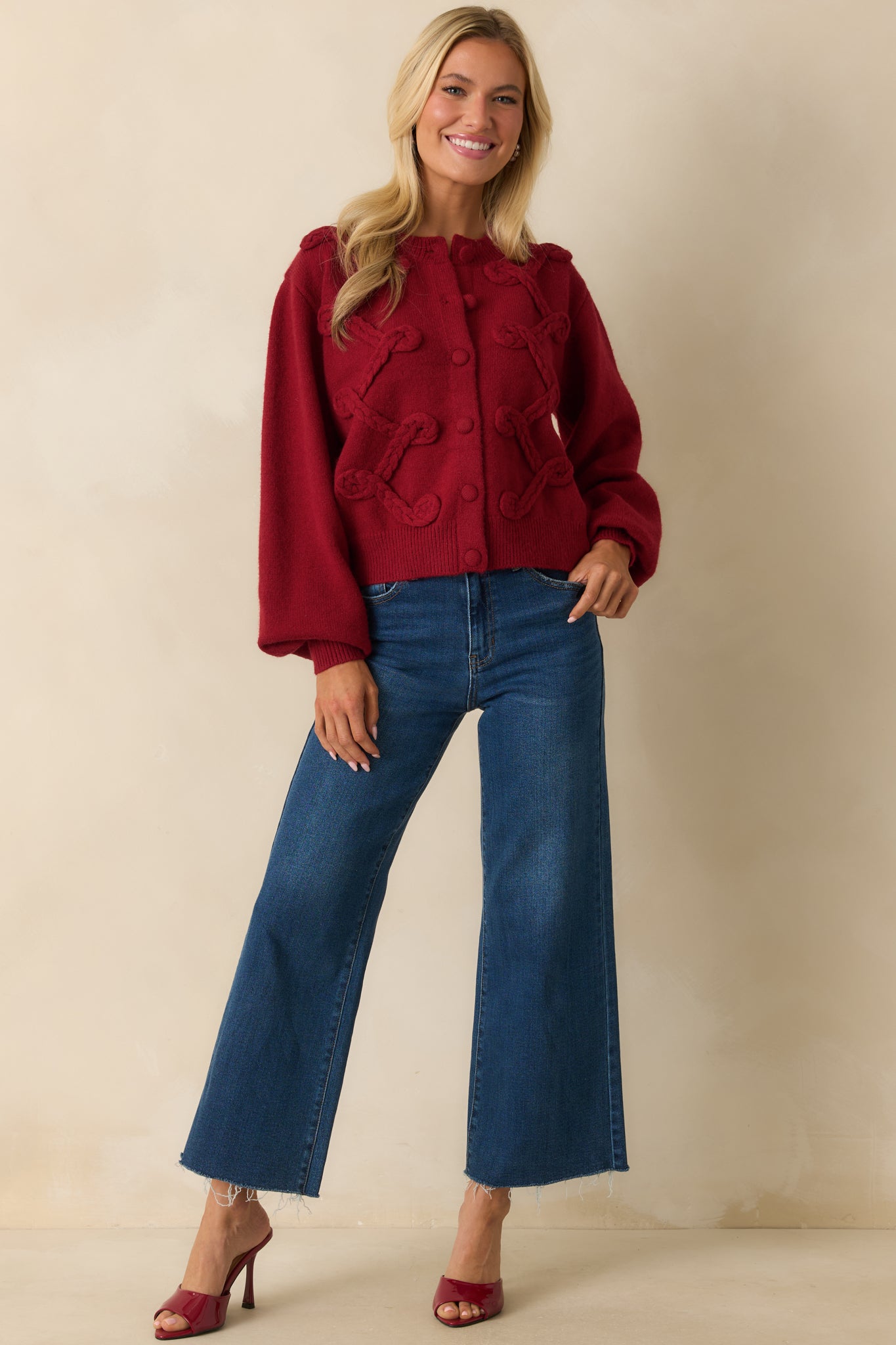 Front view of red cardigan featuring ribbed trim, long sleeves, and bold braided detailing along the front.