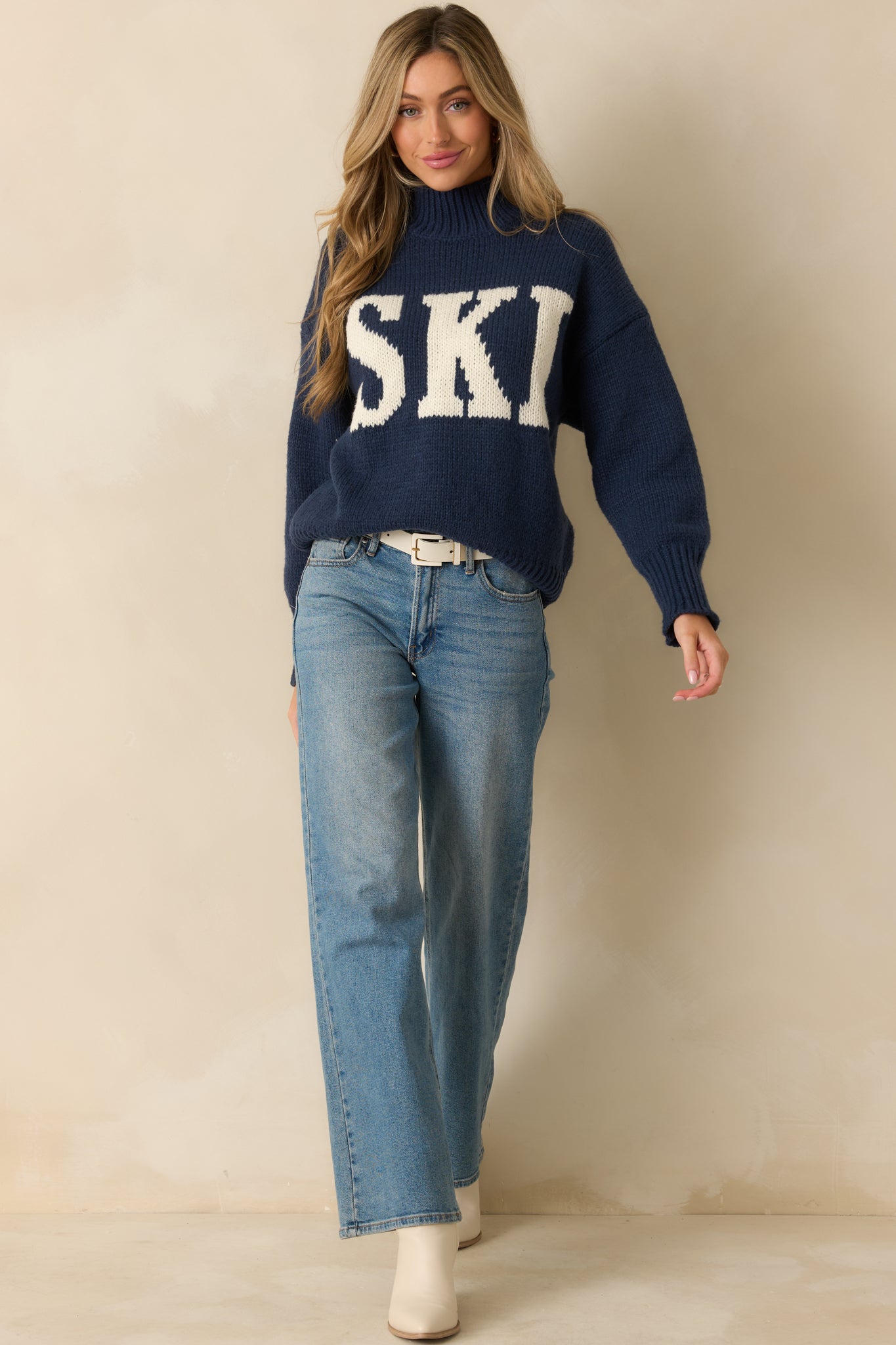 Straight-on front view highlighting the ribbed turtleneck, long sleeves, and full-length relaxed silhouette with the contrasting graphic.