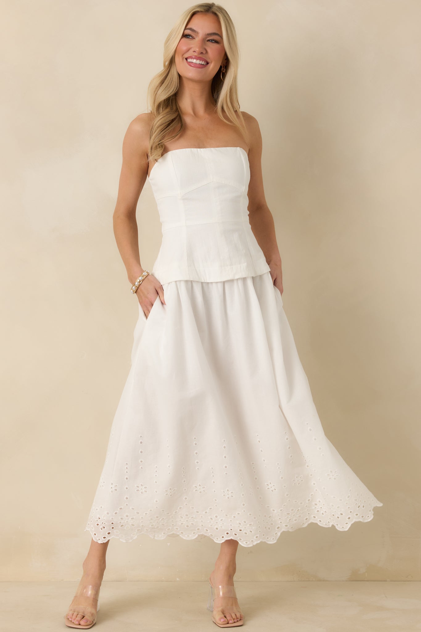 Full body front shot focusing on the balanced proportions of the structured bodice and flowing skirt, featuring a defined waist seam and embroidered hemline.