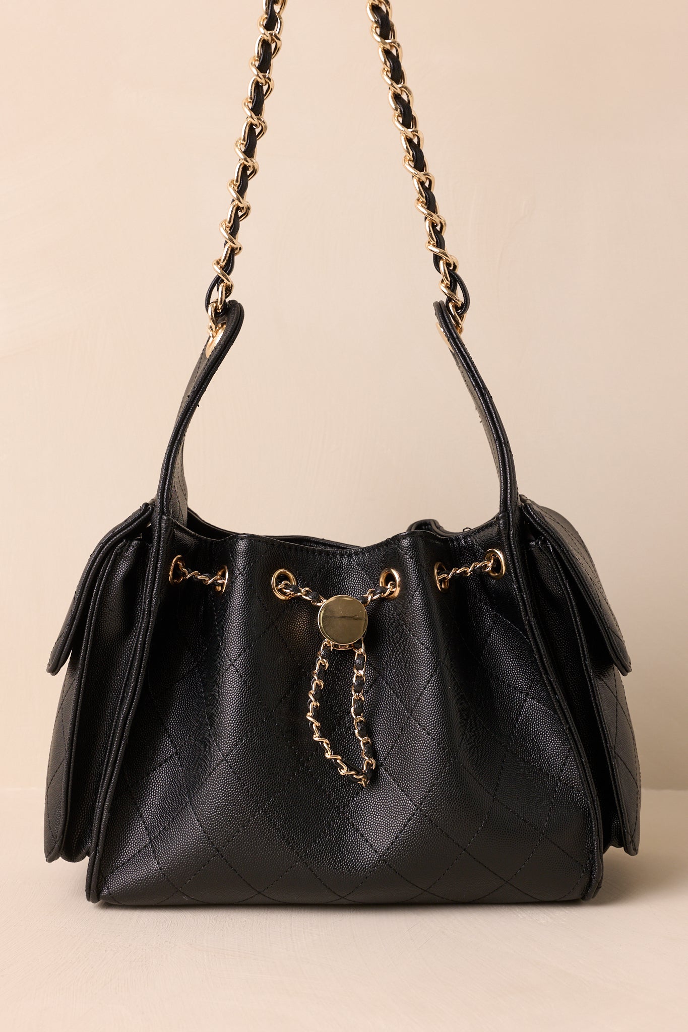 A front shot of the purse highlighting the structured silhouette and detachable faux leather cord and gold chain strap.