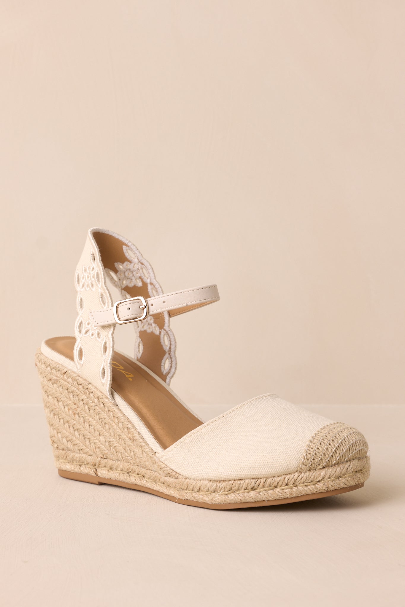 A dynamic shot capturing both the front and side of the wedges, highlighting the beige fabric, knit tip, and wedge height.