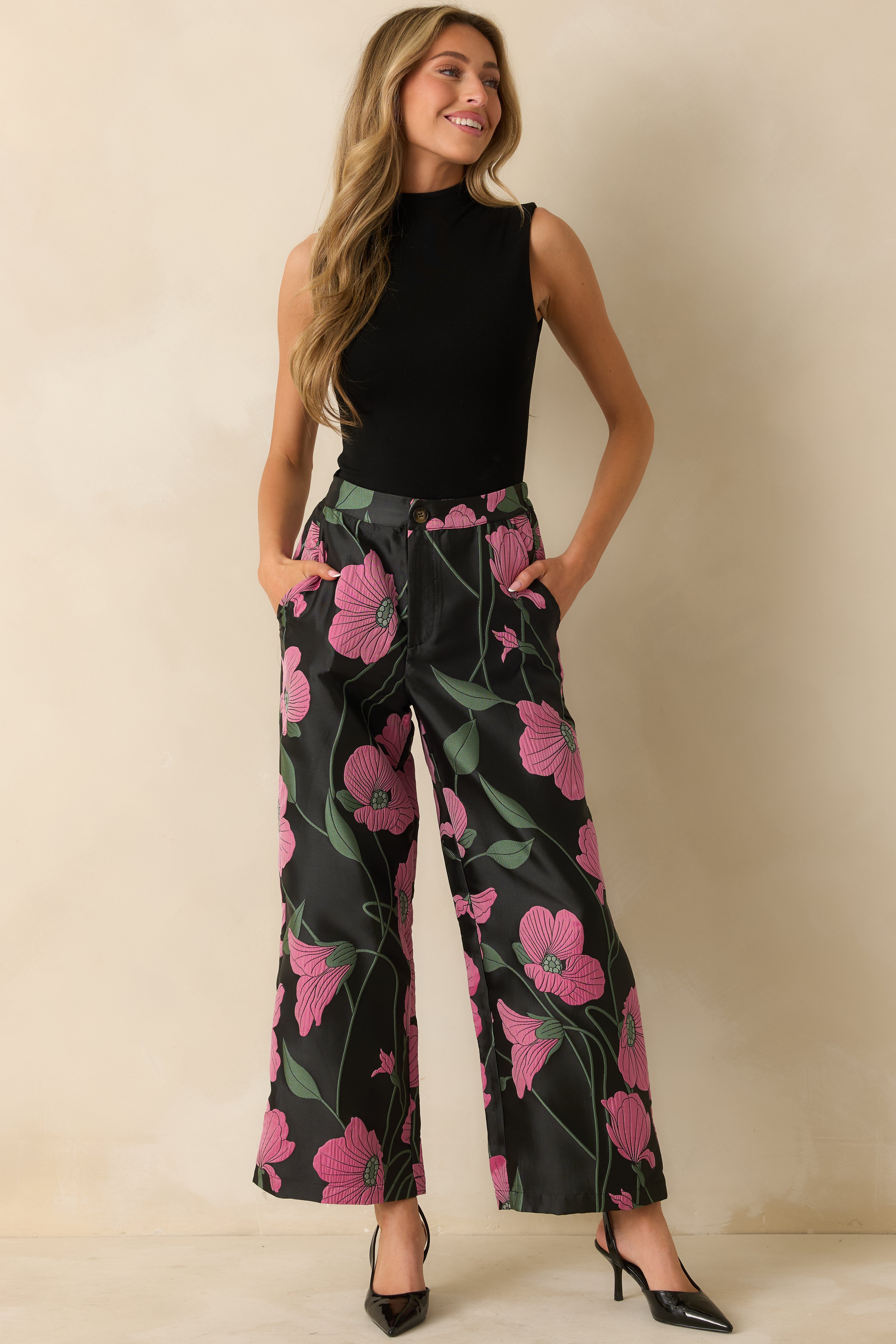 Front view of black jacquard pants featuring pink and green floral pattern, high-rise waist, and wide-leg silhouette.