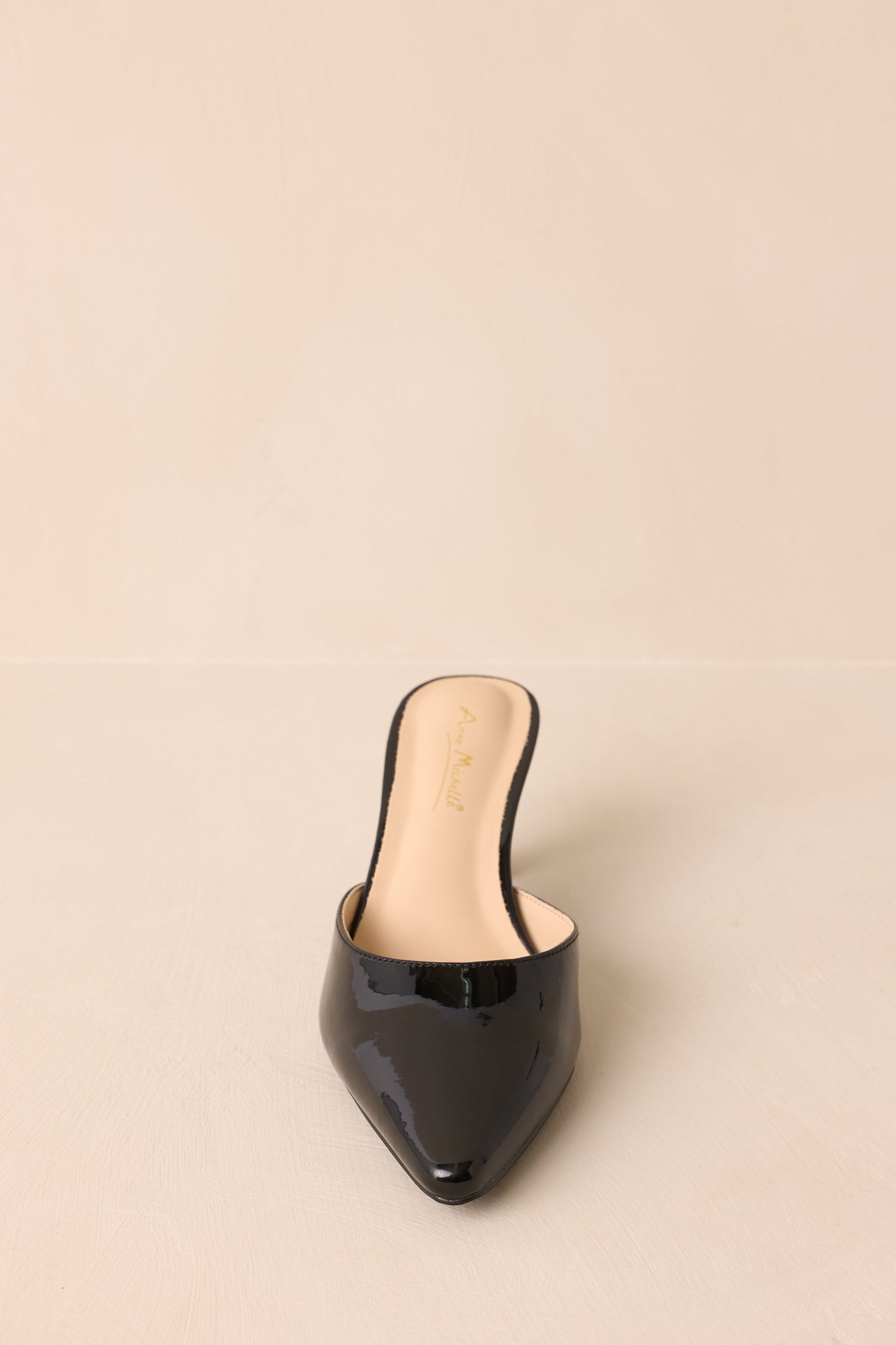 A straight-on front shot emphasizing the pointed toe design and smooth patent surface.