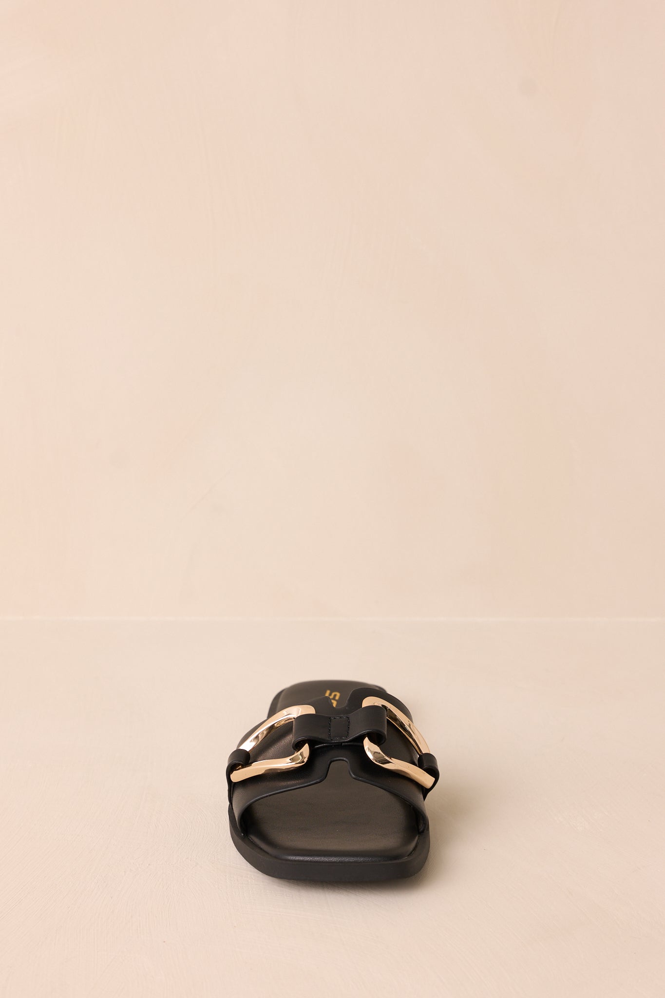 A straight-on front shot of the black sandals showcasing the square toe design and gold buckle detail.