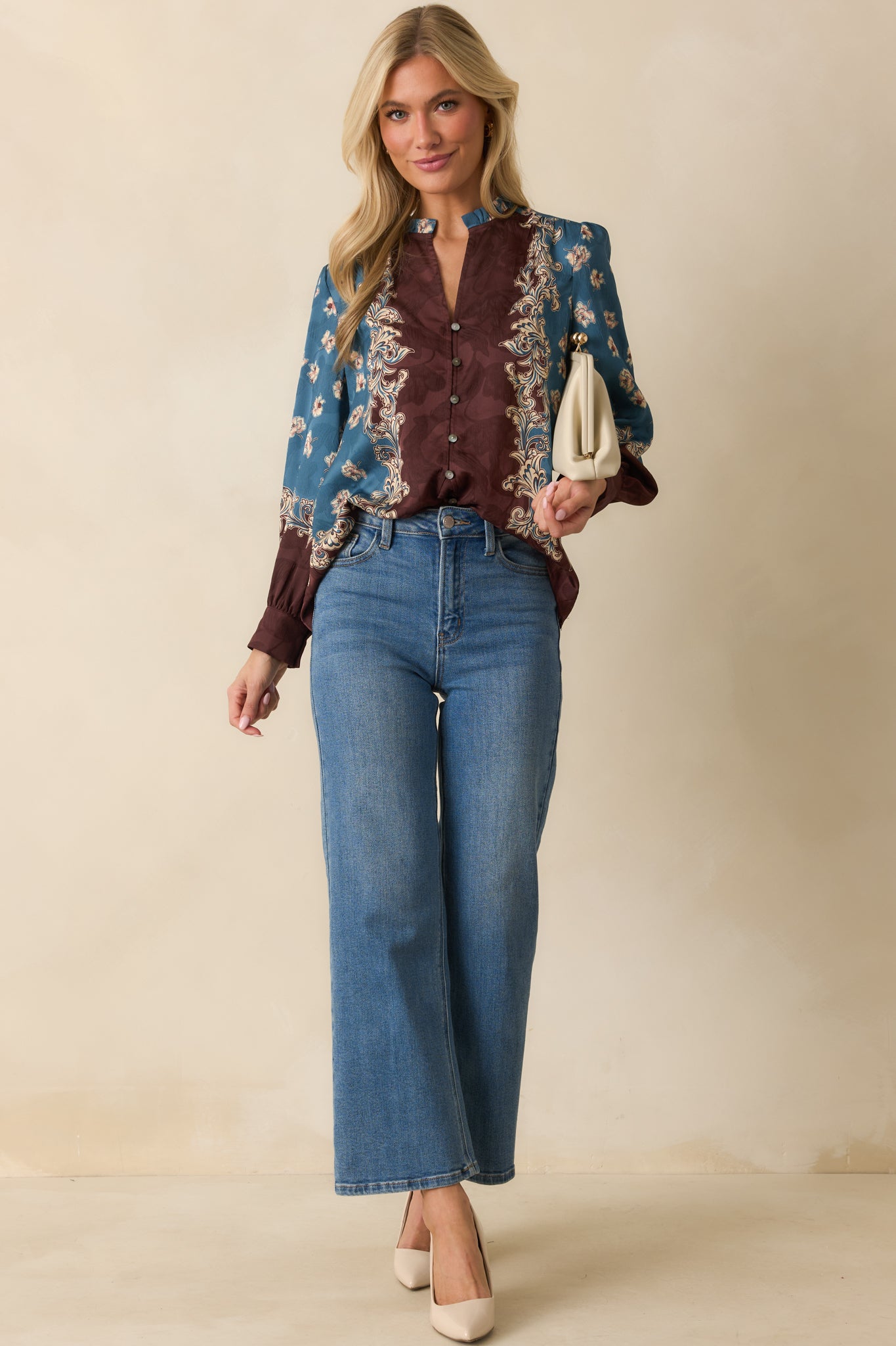 A front view of the blue blouse featuring a brown and ivory floral border print and split v-neckline.