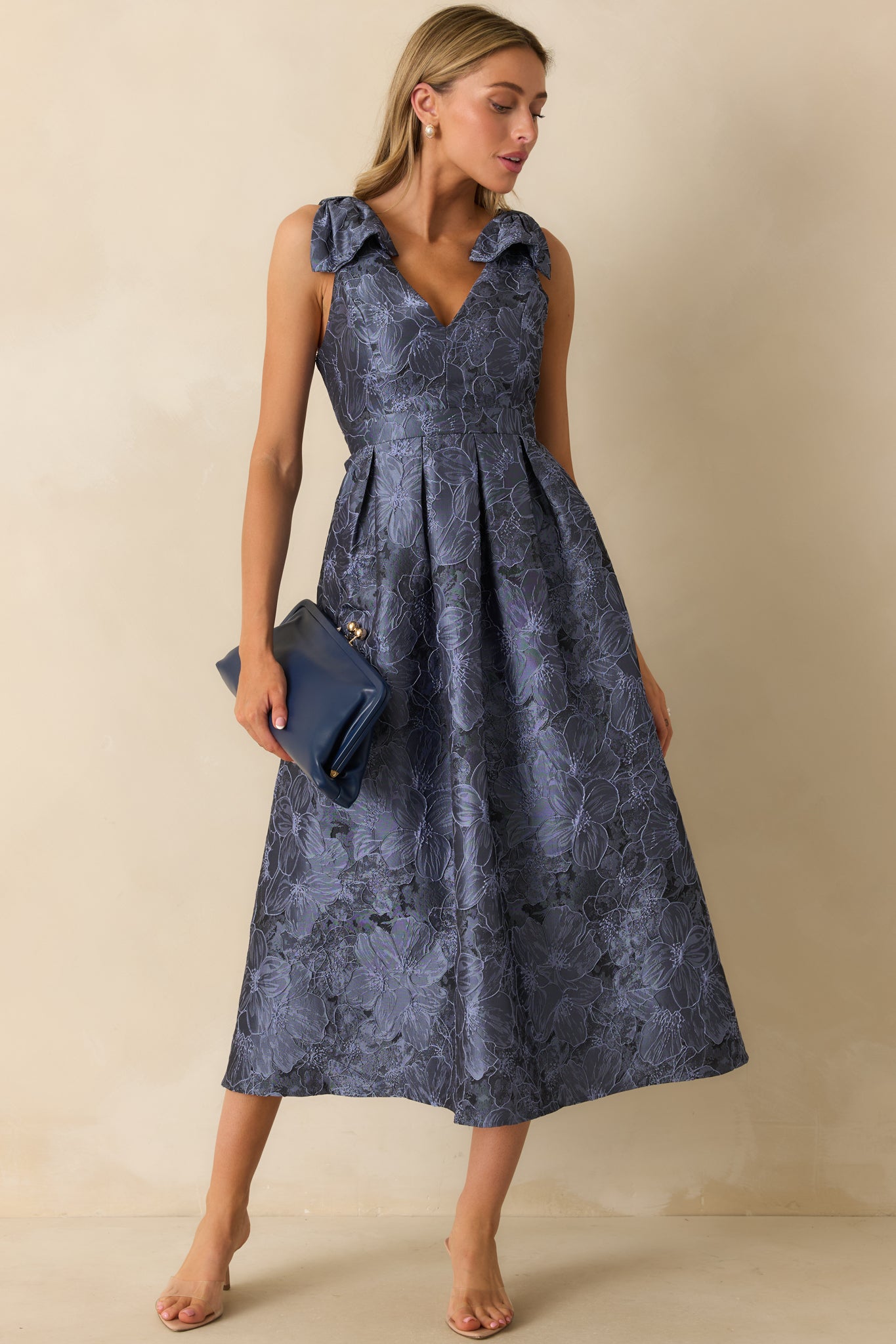 Front view of blue dress highlighting floral pattern, two functional side pockets, and adjustable bow straps.