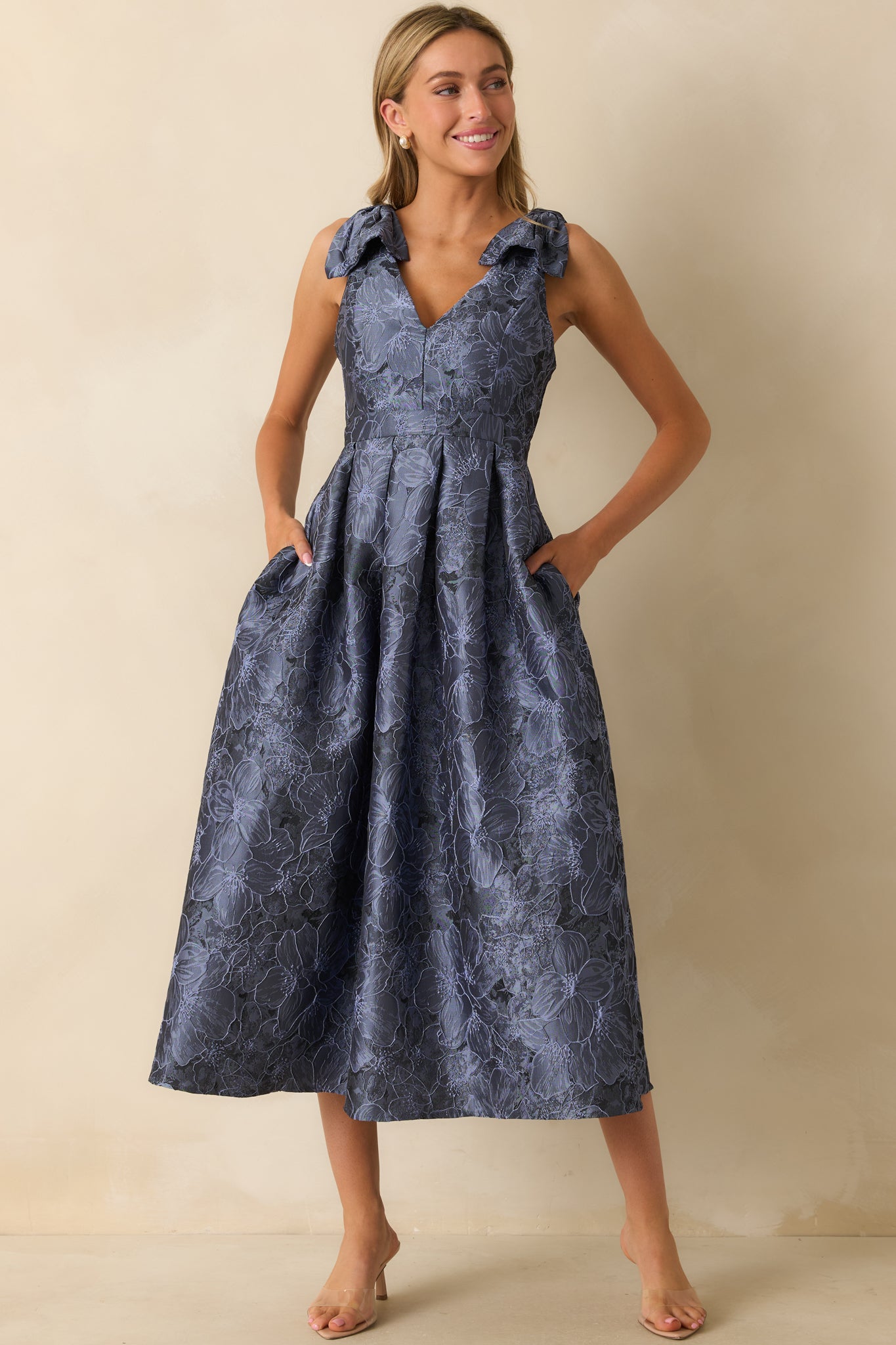 Front-facing blue midi dress with sleeveless design, v-neckline, and floral pattern with side pockets.