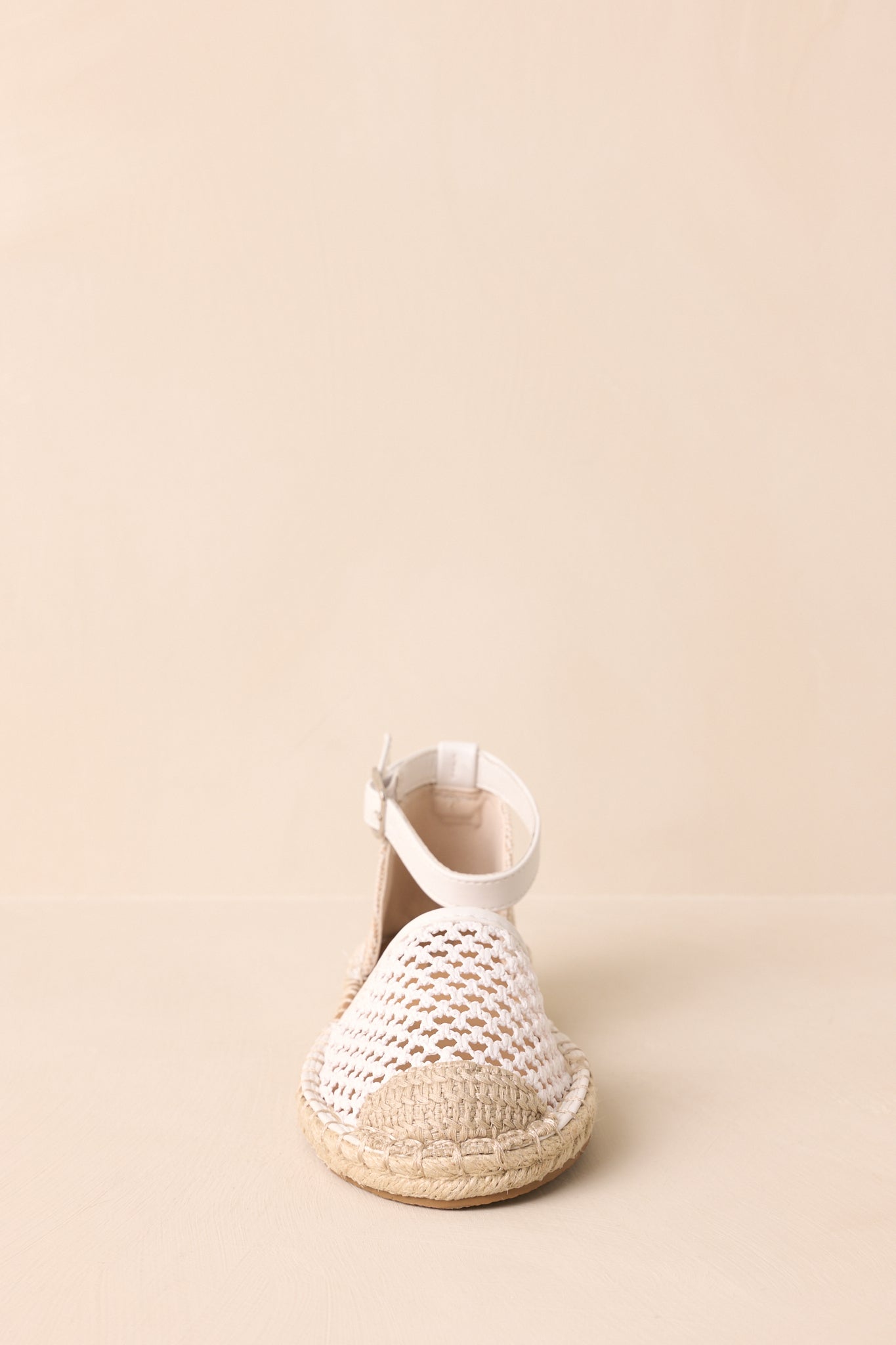 Front view of the flats displayed on a beige background showing the closed toe and woven design.