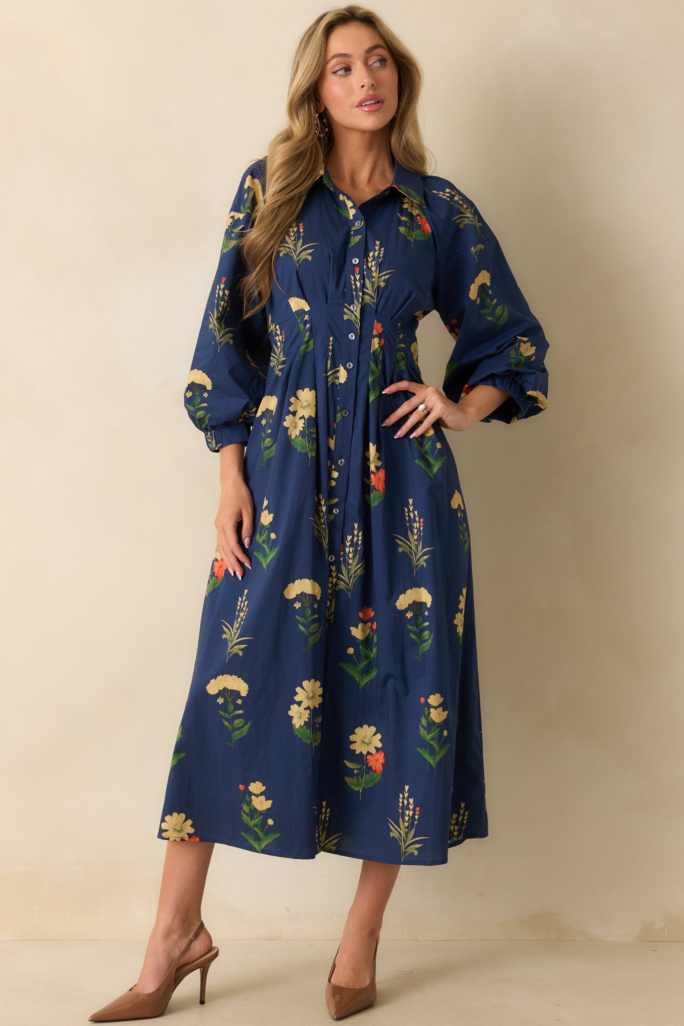 Front view of the floral navy dress emphasizing side pockets and a structured pleated waist.