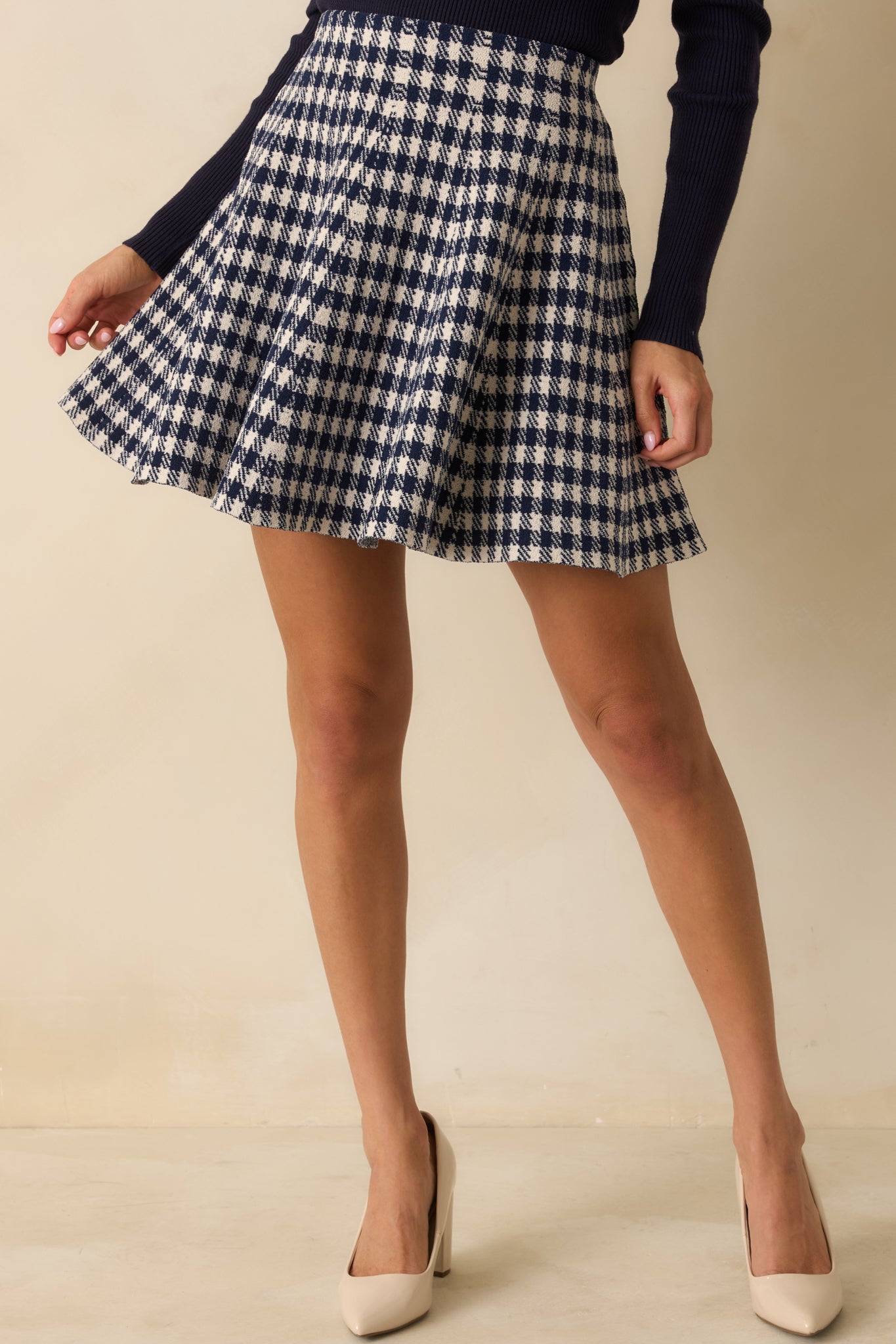 Front view focusing on the waistband and gentle flare of the knit mini skirt.