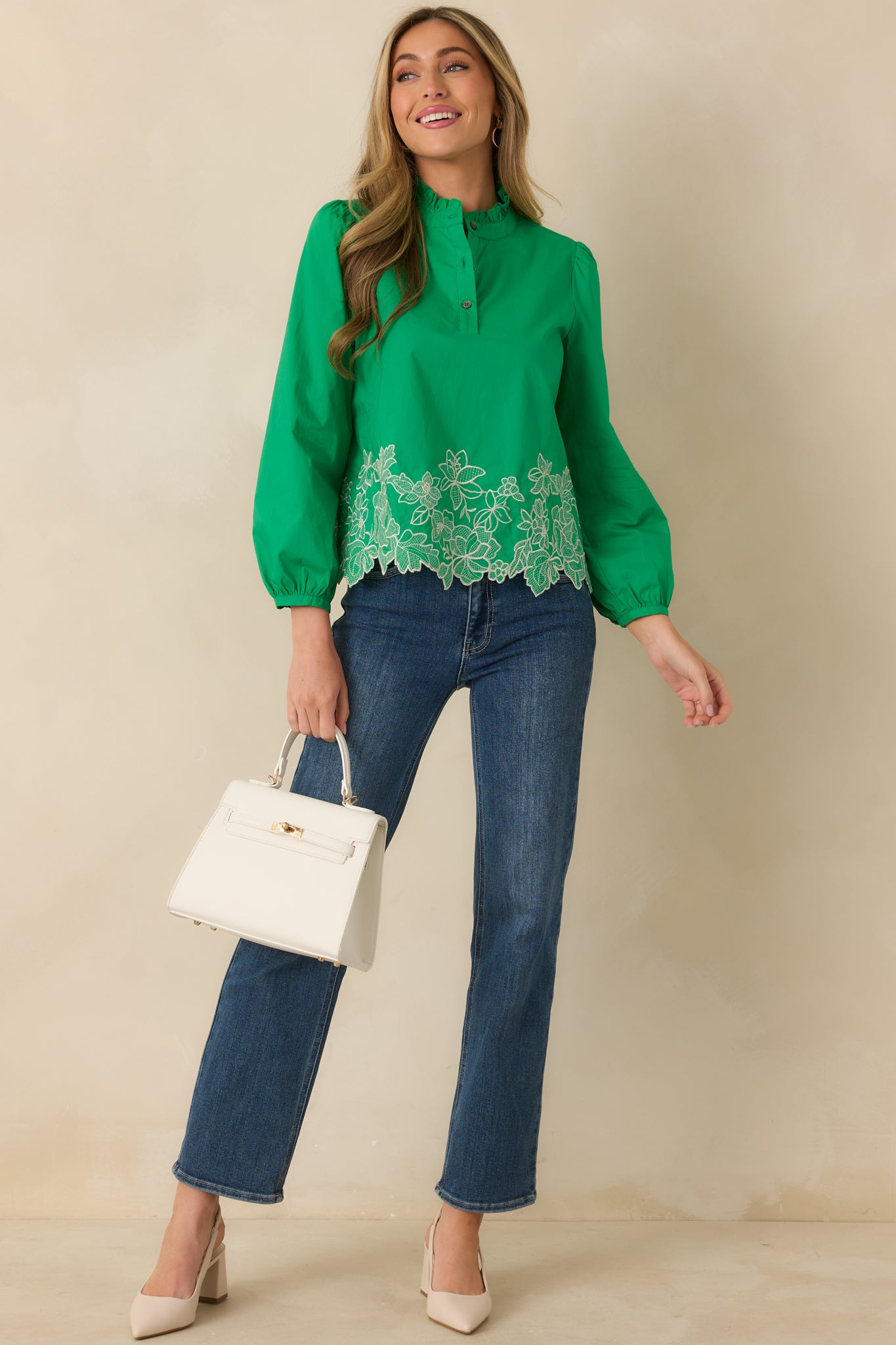 Front view of a green blouse featuring floral embroidery along the hem and a relaxed, straight fit.