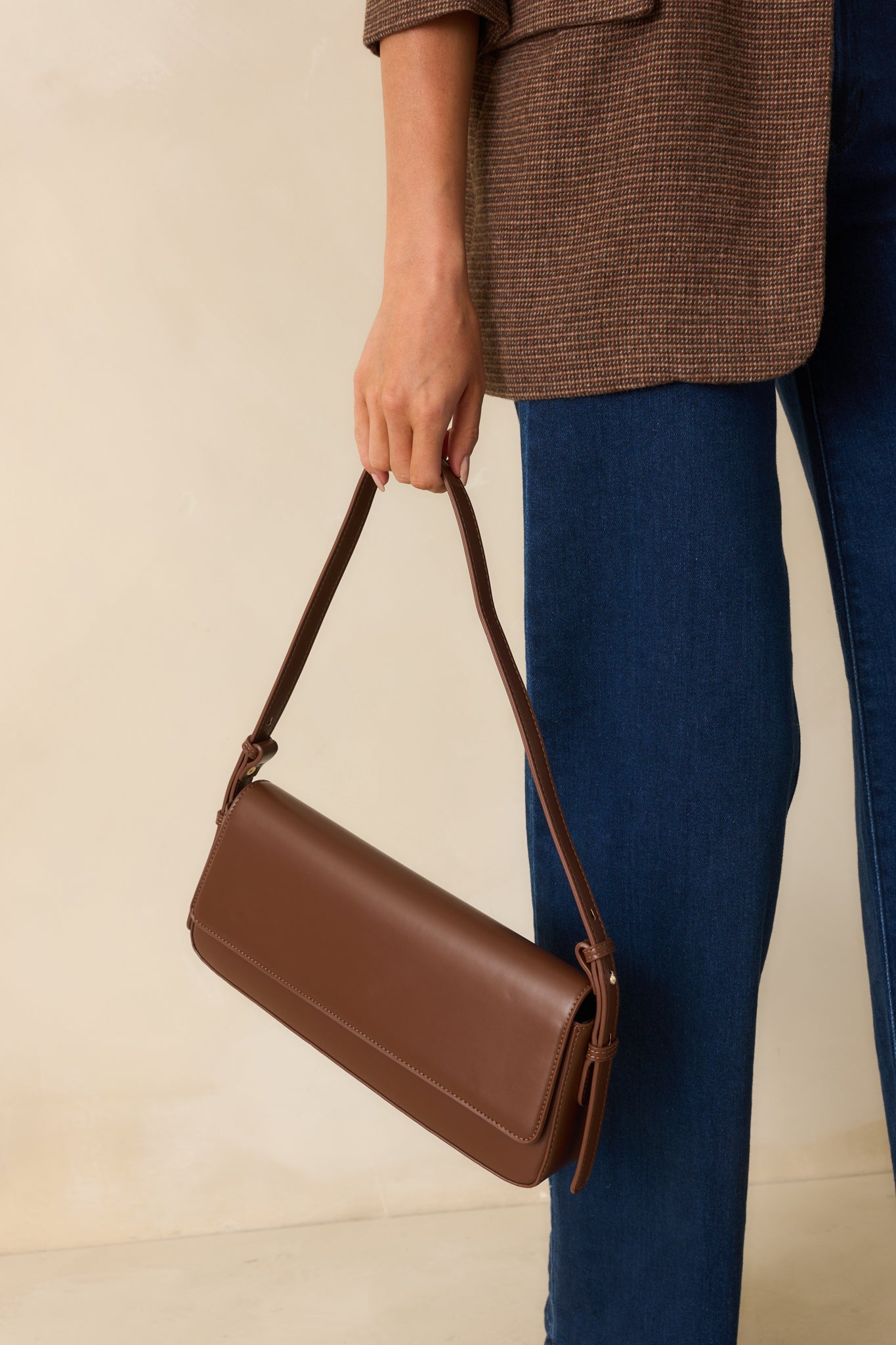 Cropped front view highlighting fold-over flap, smooth faux leather, and strap attachment