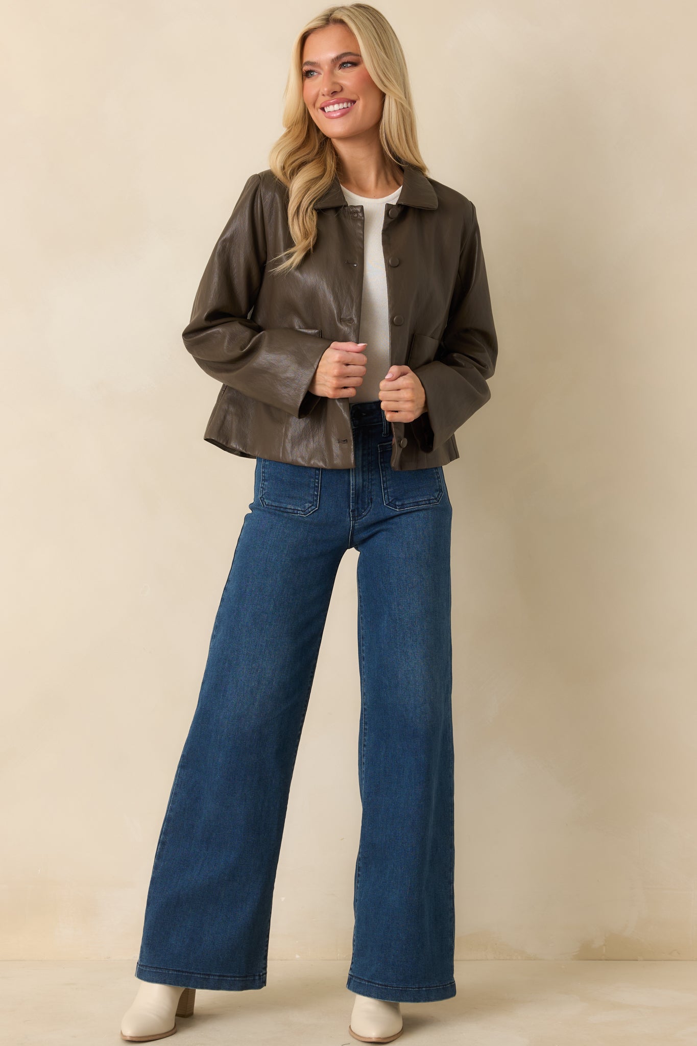 Angled front view highlighting smooth faux leather texture, boxy silhouette, and long sleeves.